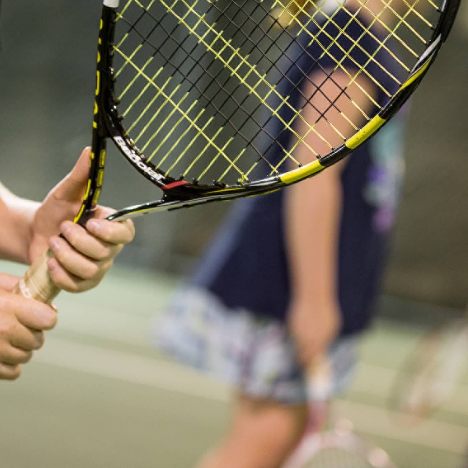 Close-up of hands holding yellow-and-black tennis racket