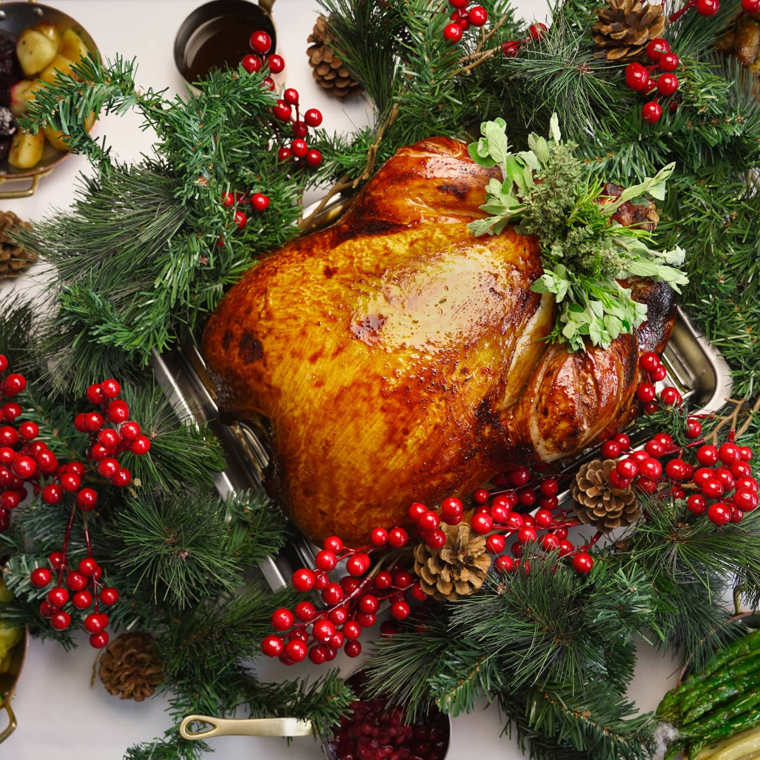 Festive whole turkey with holly berry and pine cone garnish, surrounded by side dishes
