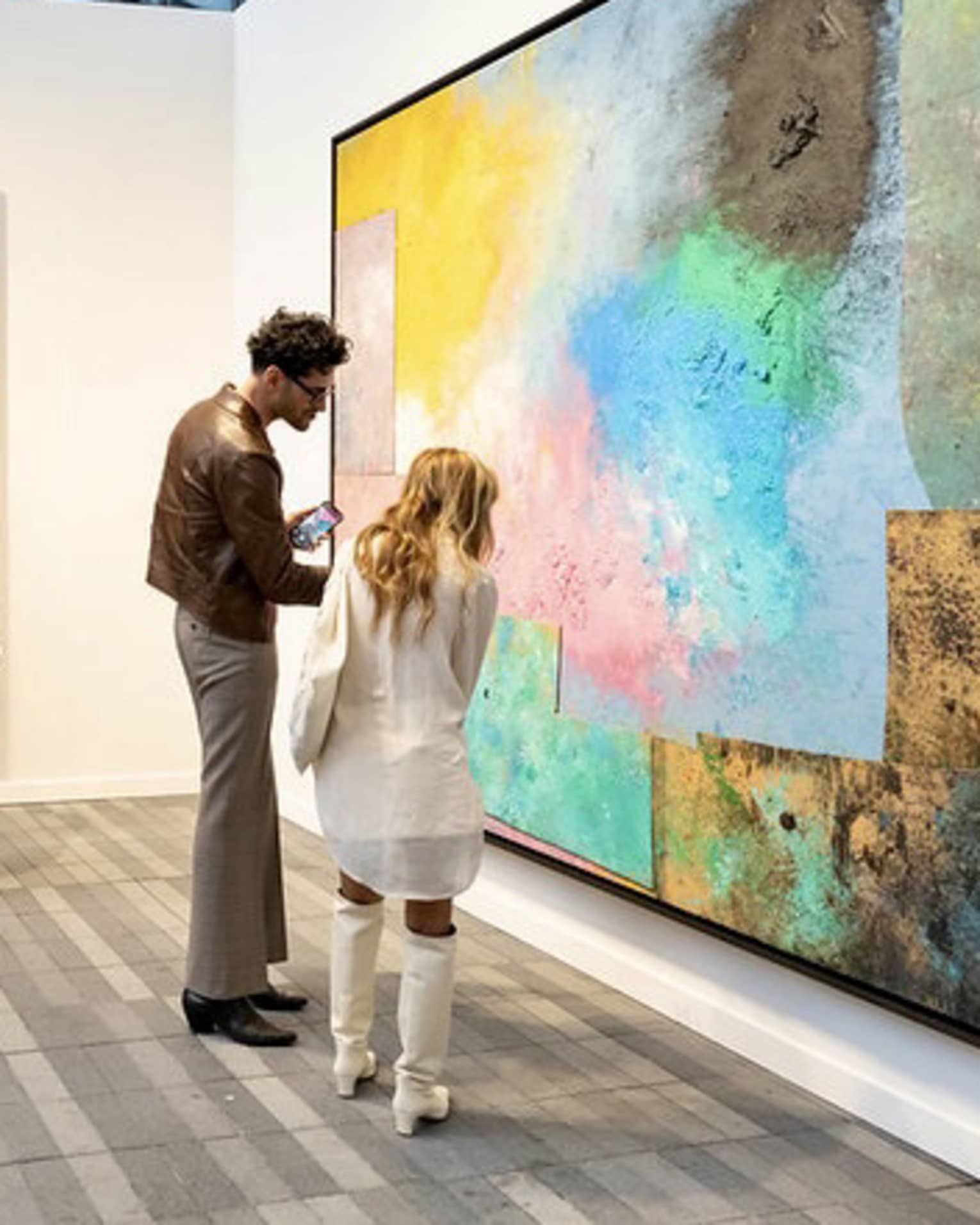People observing large paintings at an art gallery