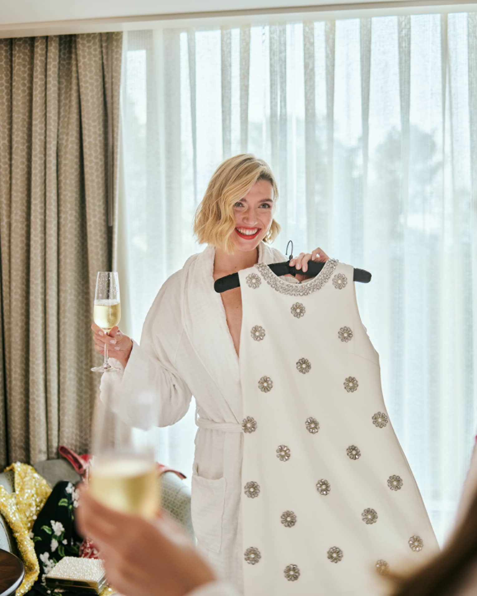 A person wearing a robe and holding a dress on a hanger