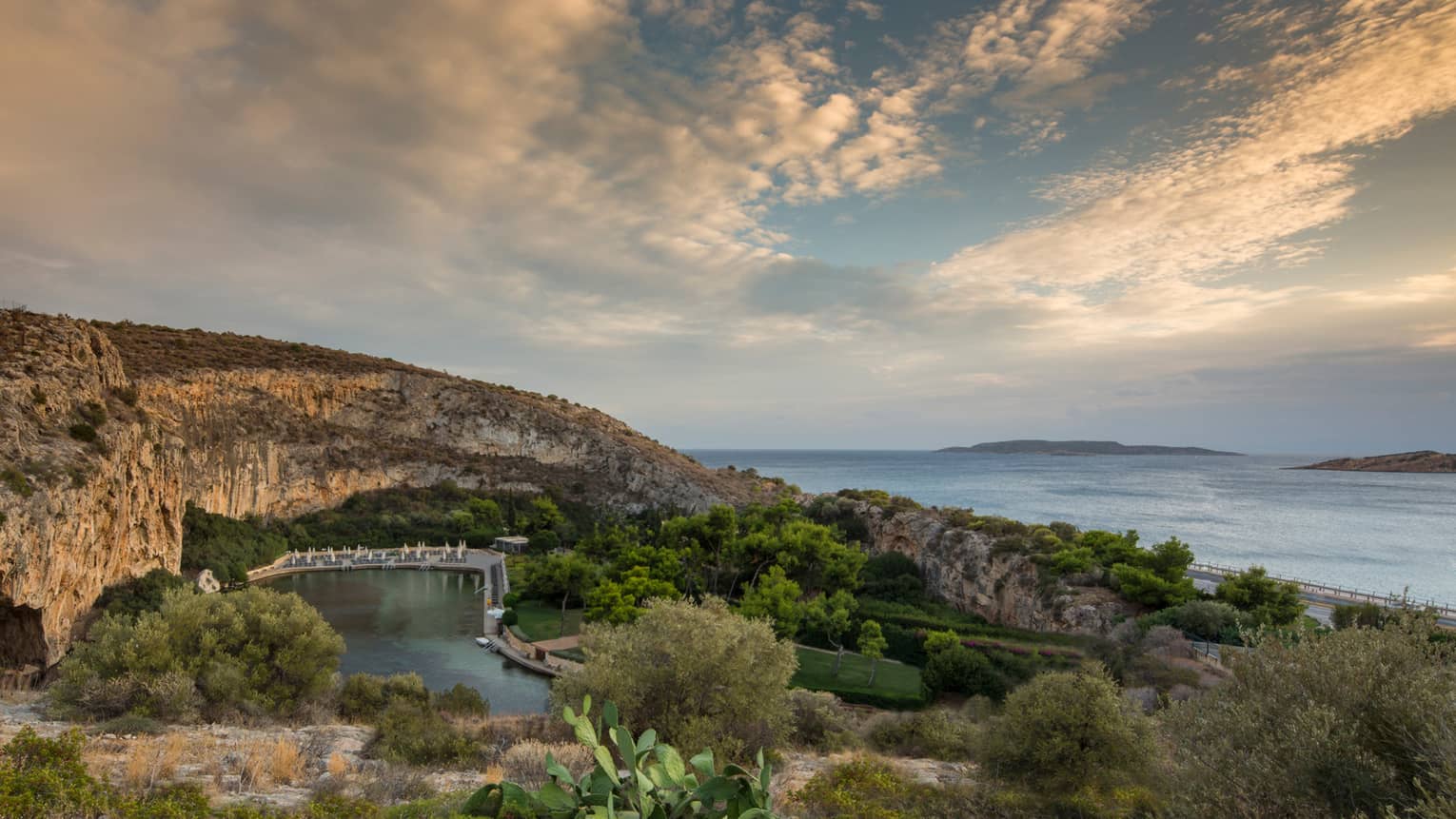 View of Vouliagmeni with rocky hill, green trees and shrubs overlooking ocean