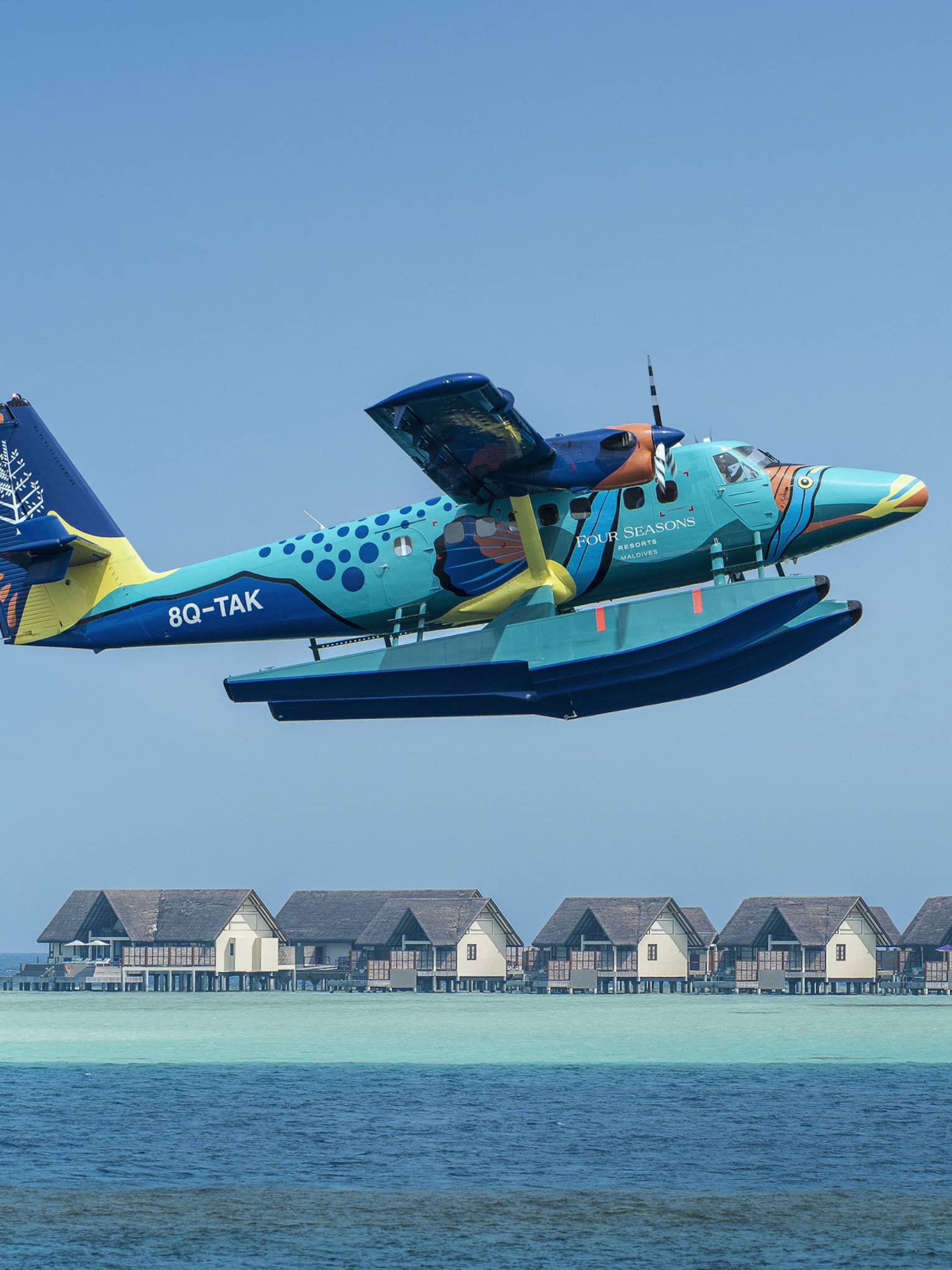 Maldives Sea Plane taking off with water villas and palm trees in the background