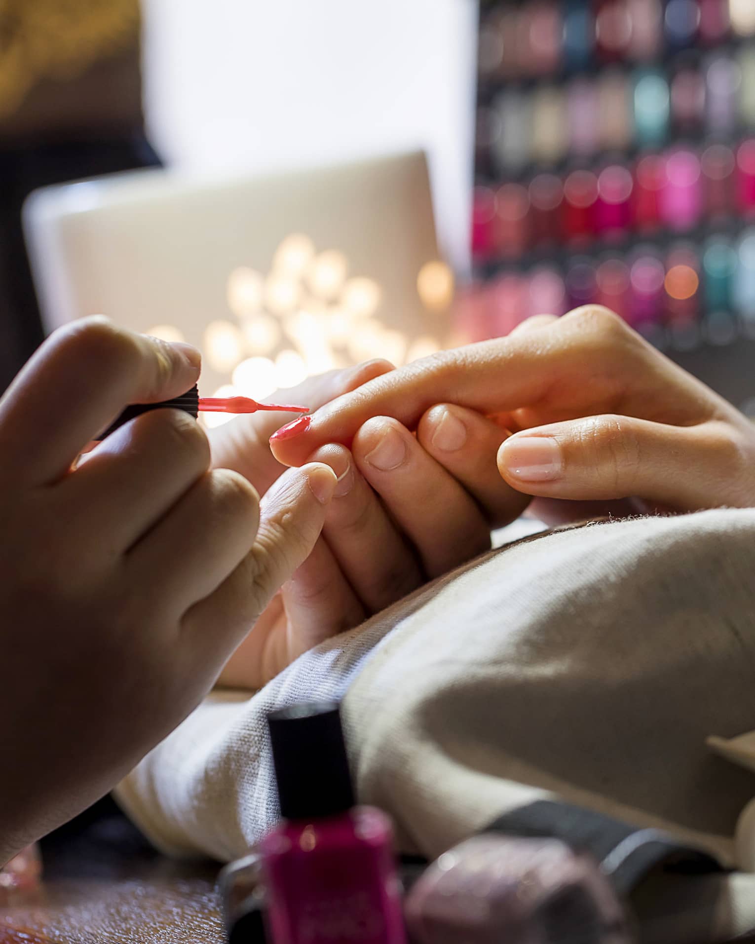 Close-up of manicure, hands resting on pillow as nails painted