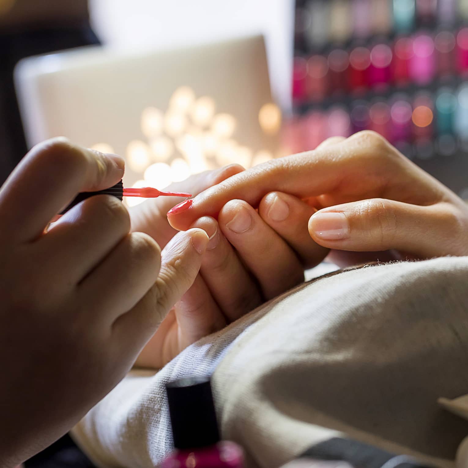 Close-up of manicure, hands resting on pillow as nails painted