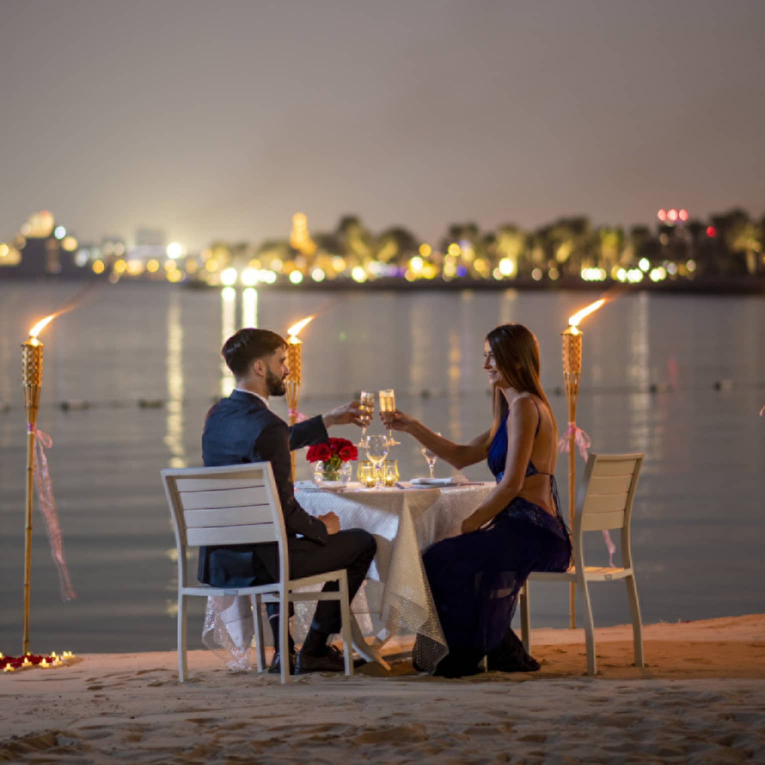 A couple dines along the gulf with the Doha city skyline in the background.