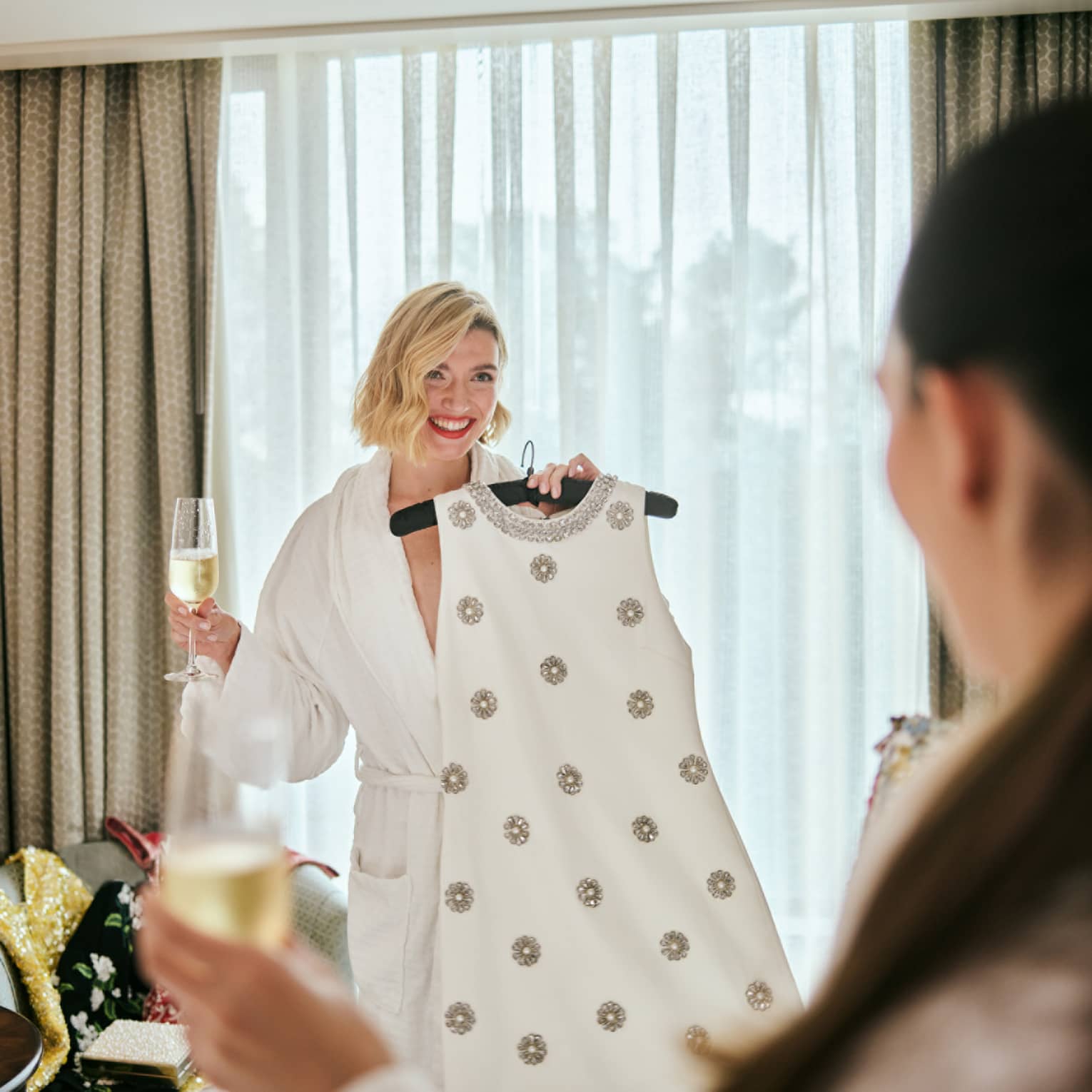 A person wearing a robe and holding a dress on a hanger