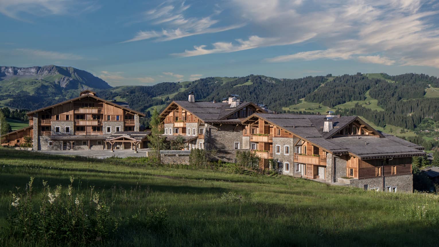 Four Seasons Hotel Megeve rustic ski resort at edge of meadow, mountains
