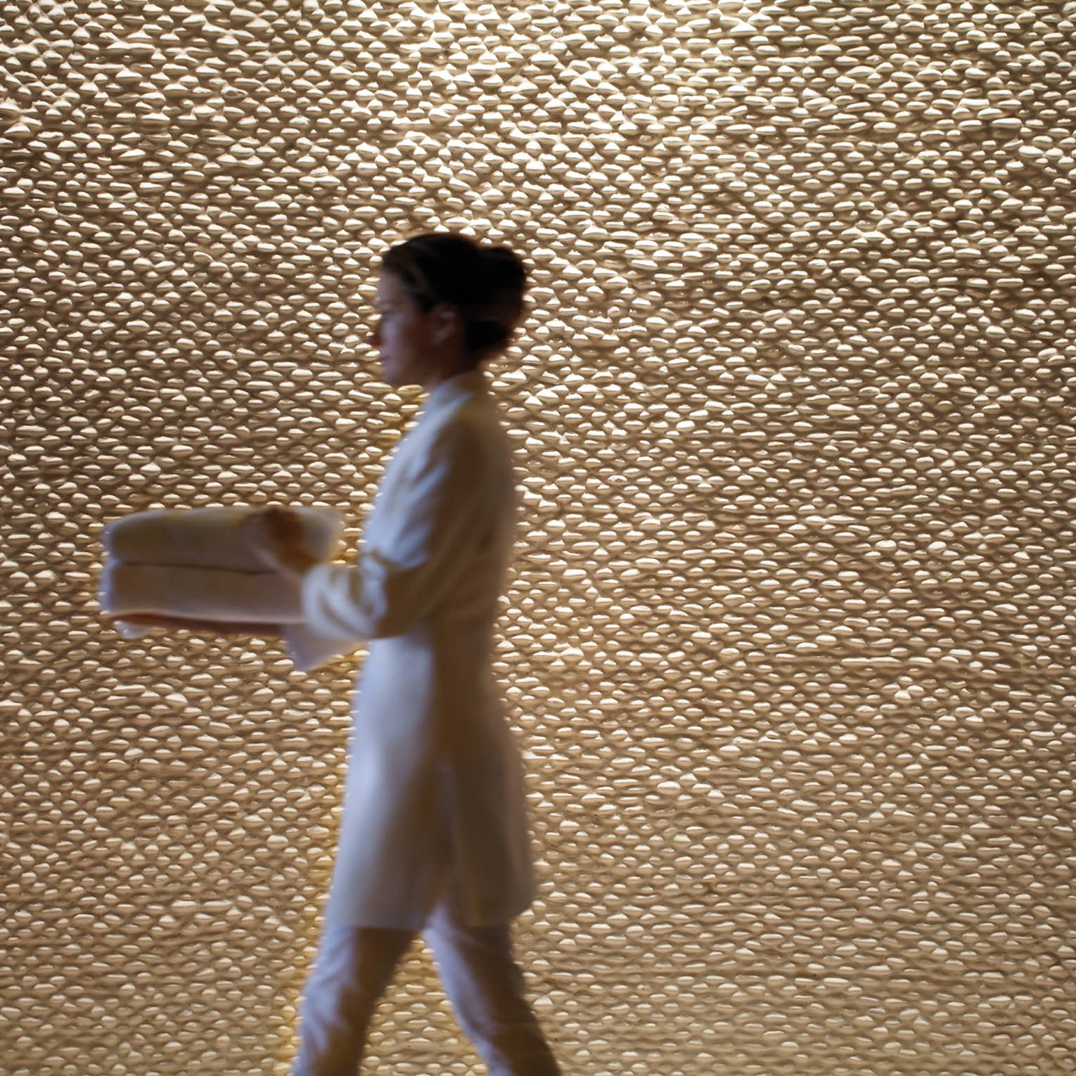 A woman in a spa robe walking by a wall.