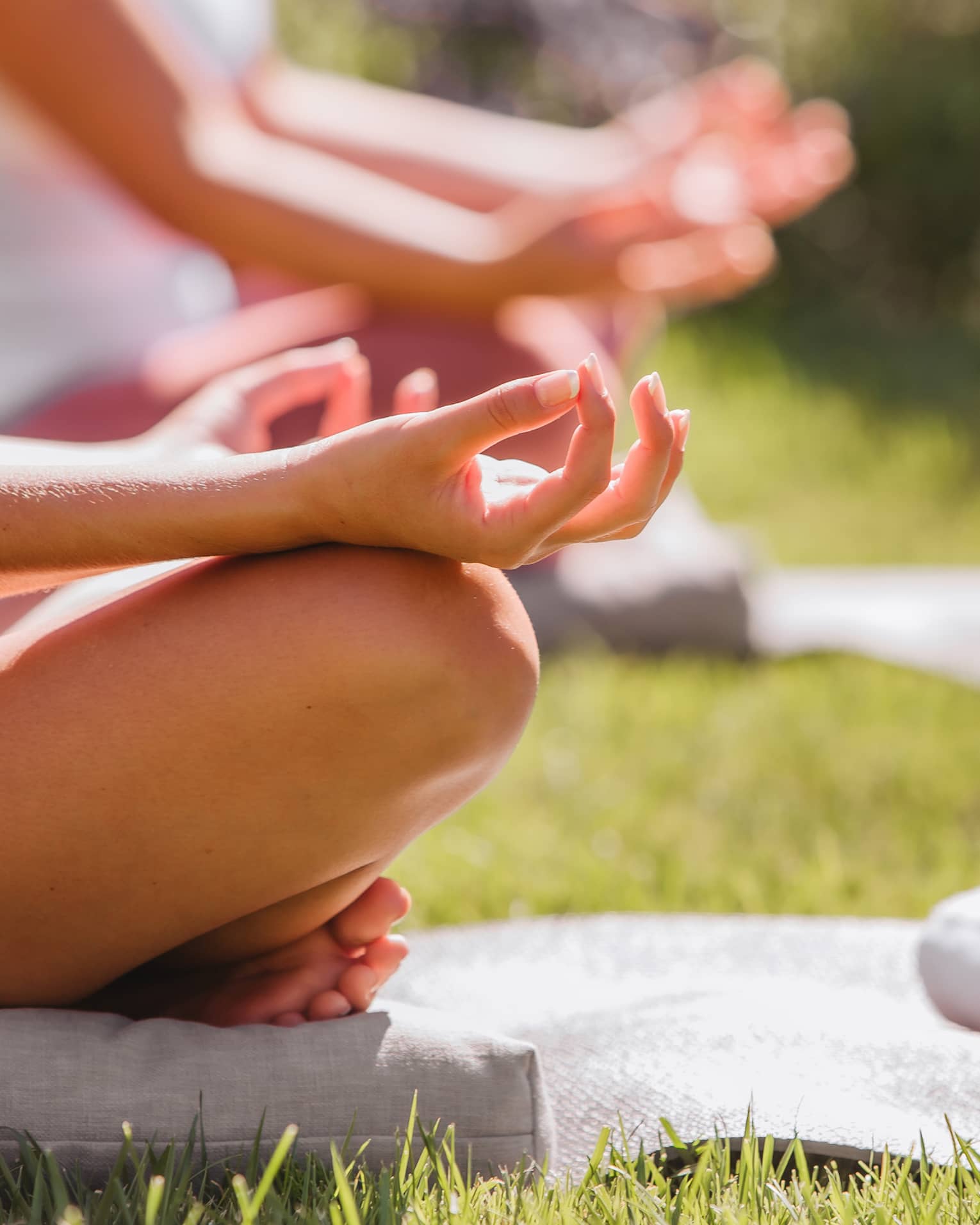 A group doing yoga outside with mats and towels.