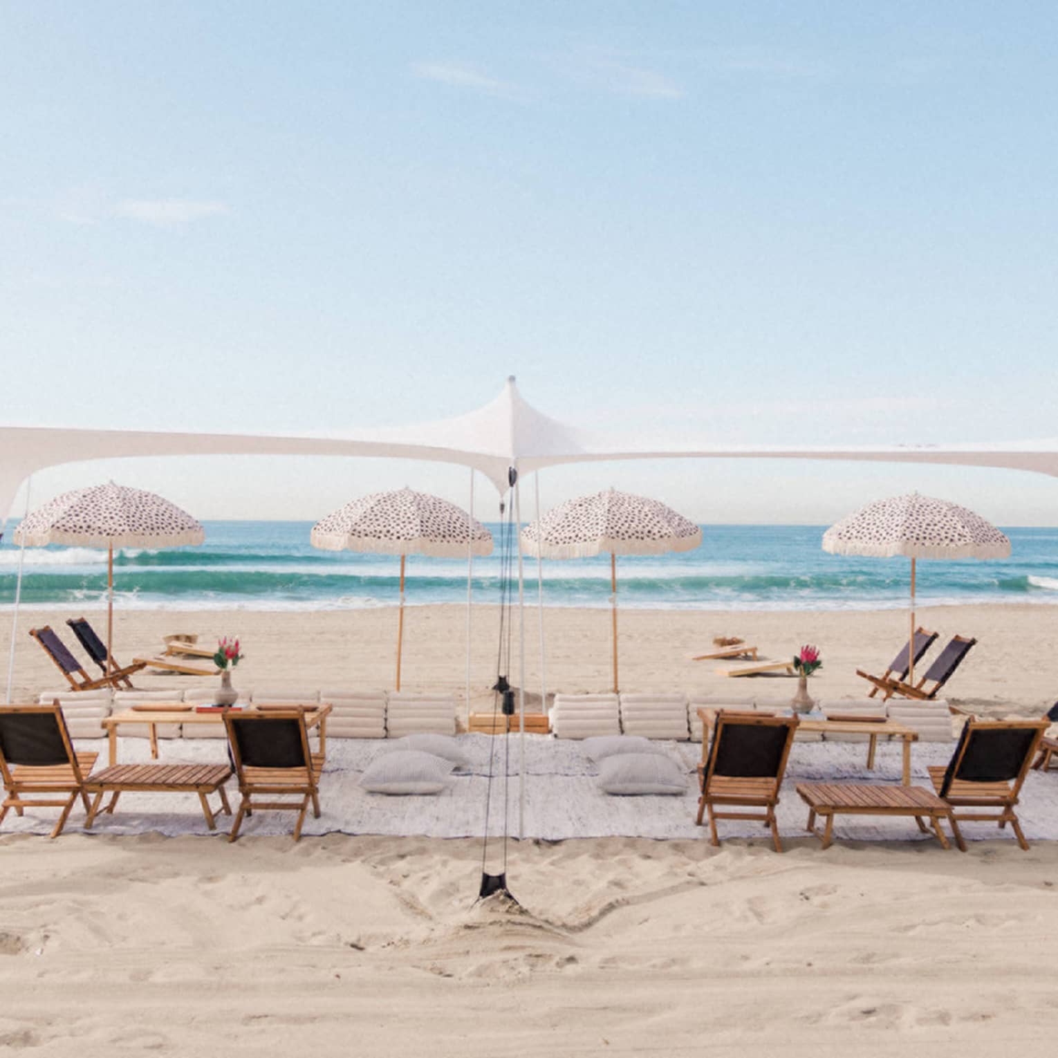 A tent with umbrellas and lounge chairs on a beach