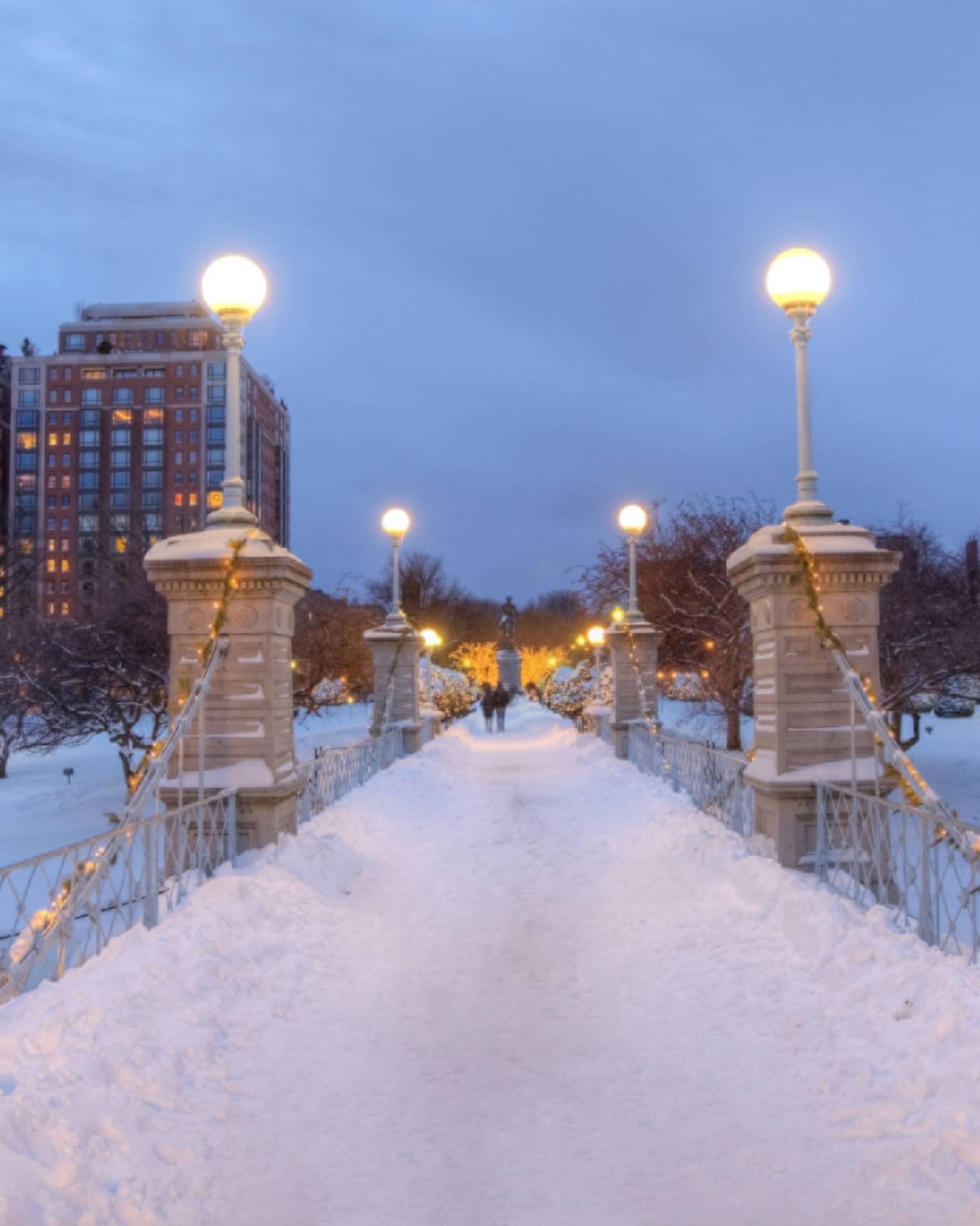 Bridge at night time covered in snow with city buildings in the background