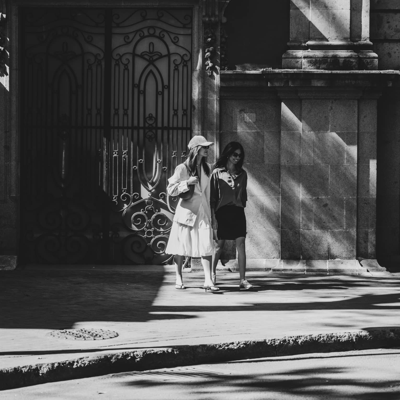 Two people stroll along a city sidewalk.
