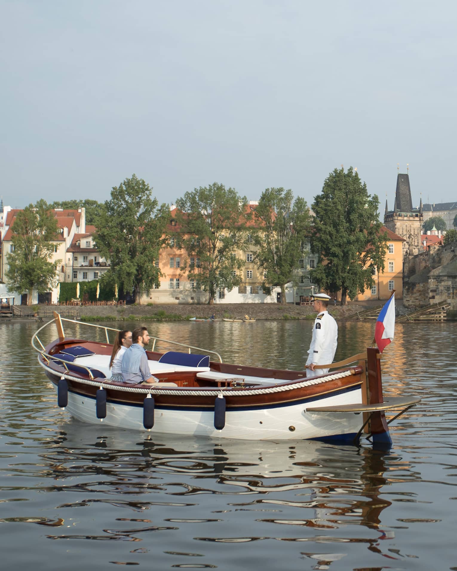Couple enjoy river boat trip in Prague near small bridge