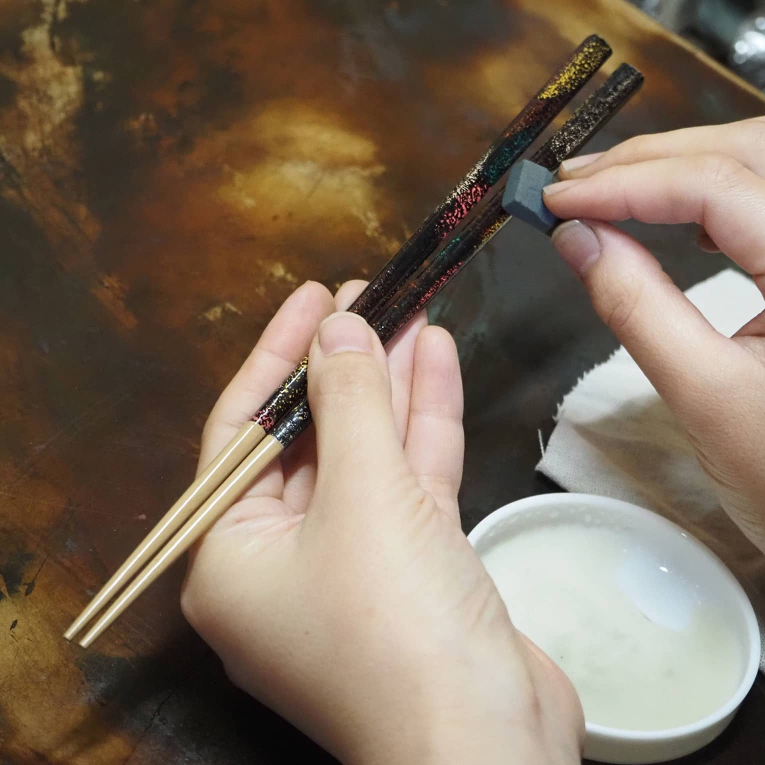 Hands apply Japanese lacquer to customize artisan chop sticks