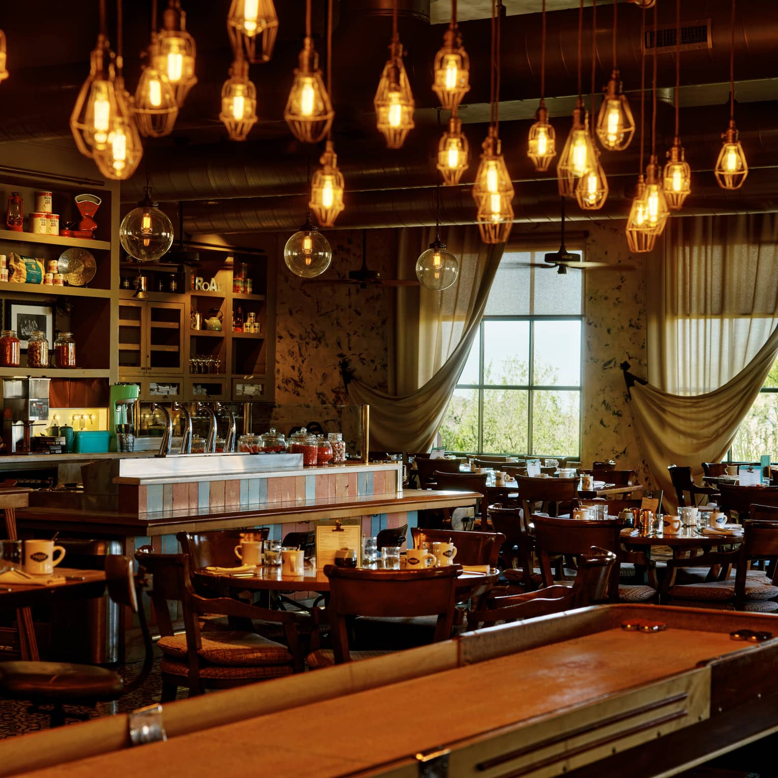 Proof restaurant with shuffleboard table and hanging lights, at Four Seasons Resort Scottsdale