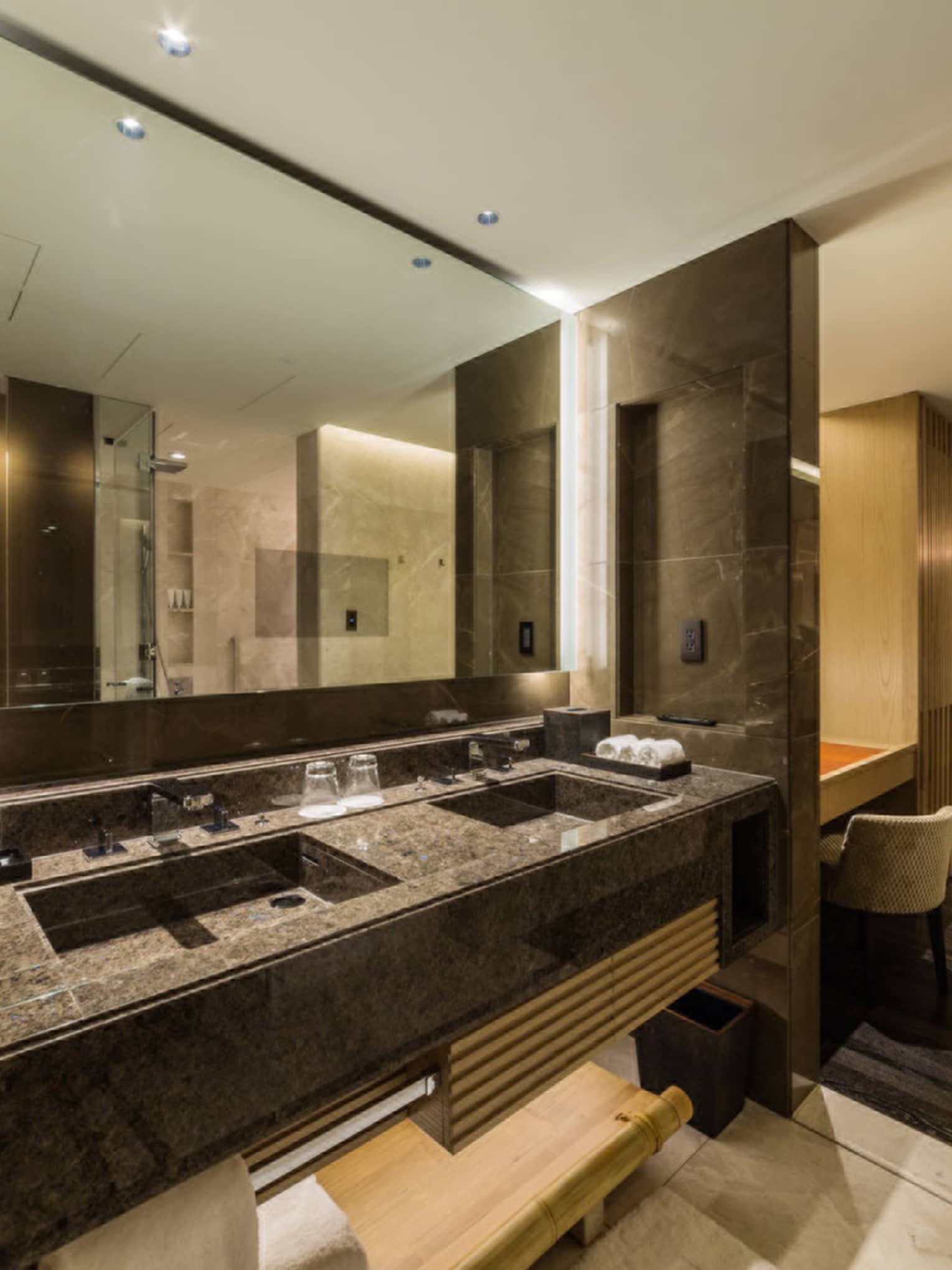 Luxury bathroom with a double-sink vanity, large mirror and ambient lighting, leading to the bedroom area at Four Seasons