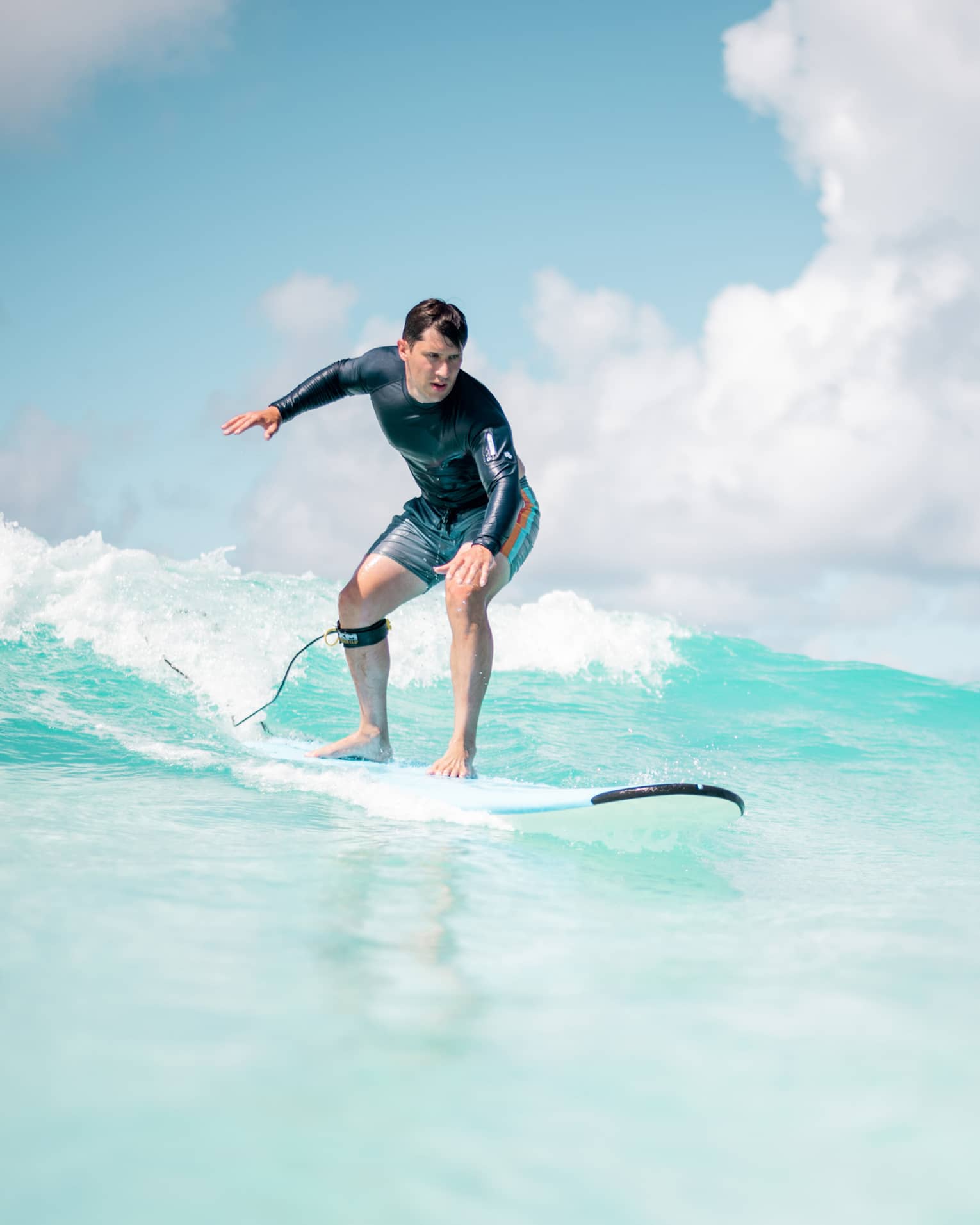 Man balances on surf board over wave