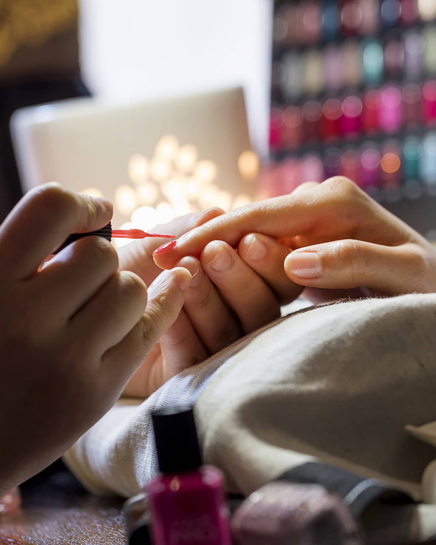 Close-up of manicure, hands resting on pillow as nails painted