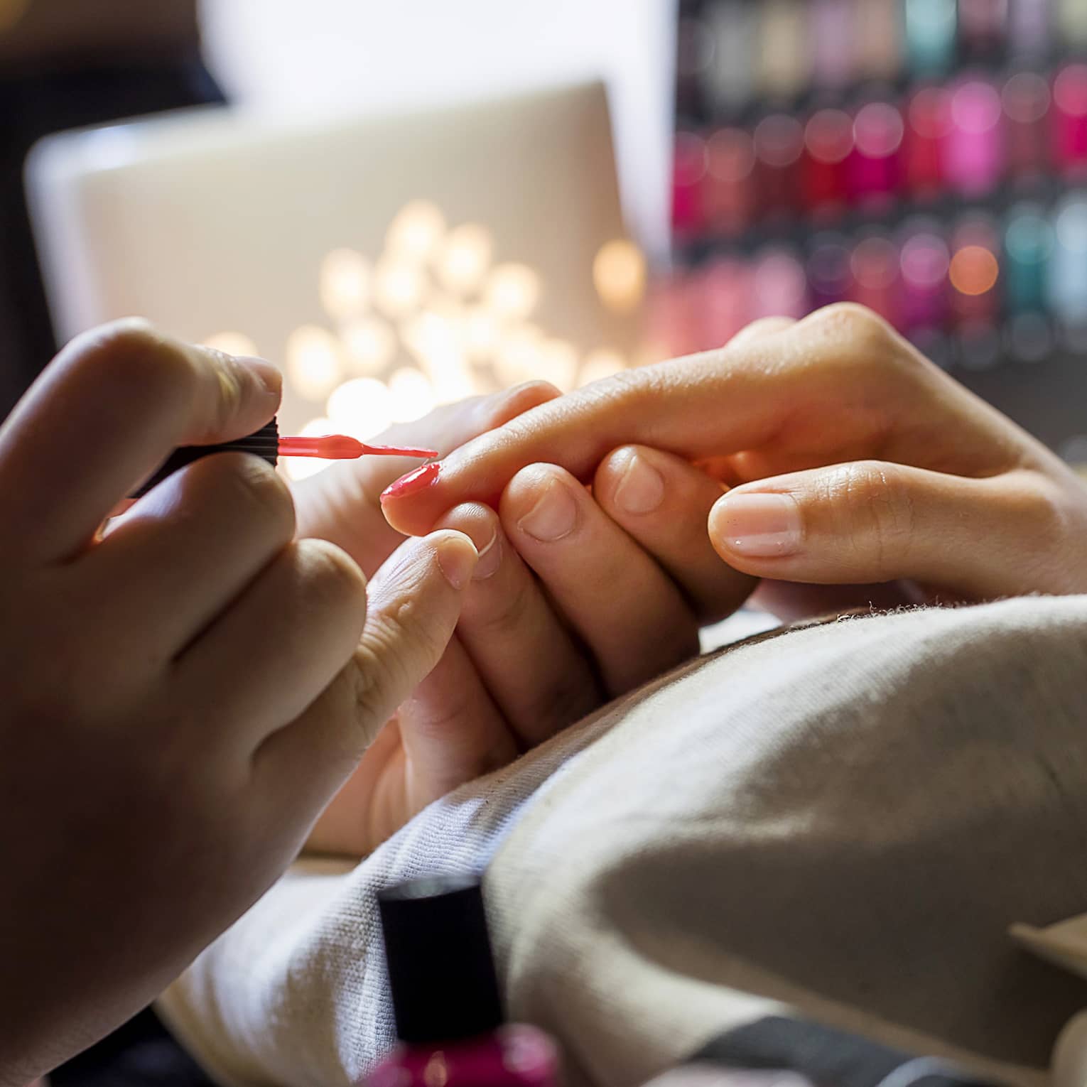 Close-up of manicure, hands resting on pillow as nails painted