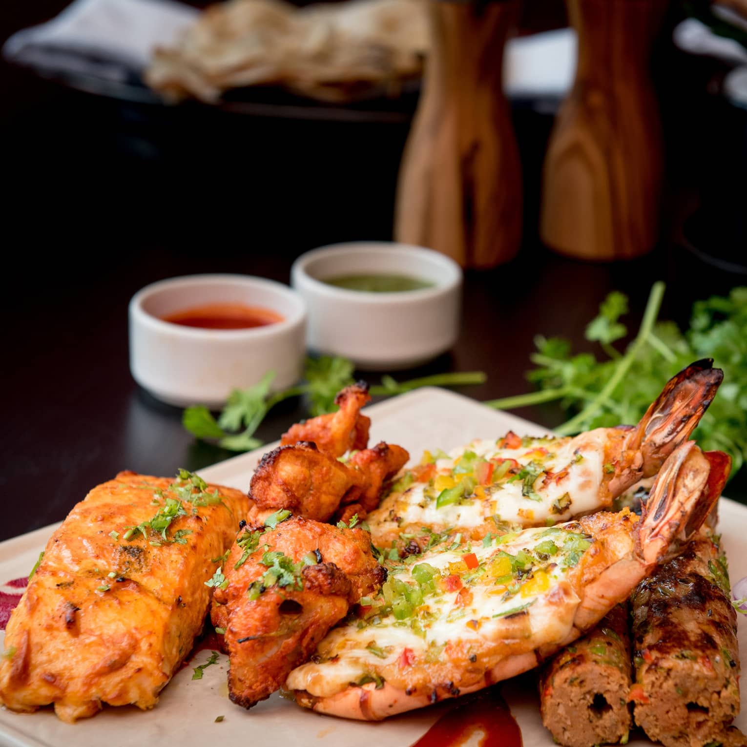 Seafood and meat kebabs garnished with fresh herbs on white platter