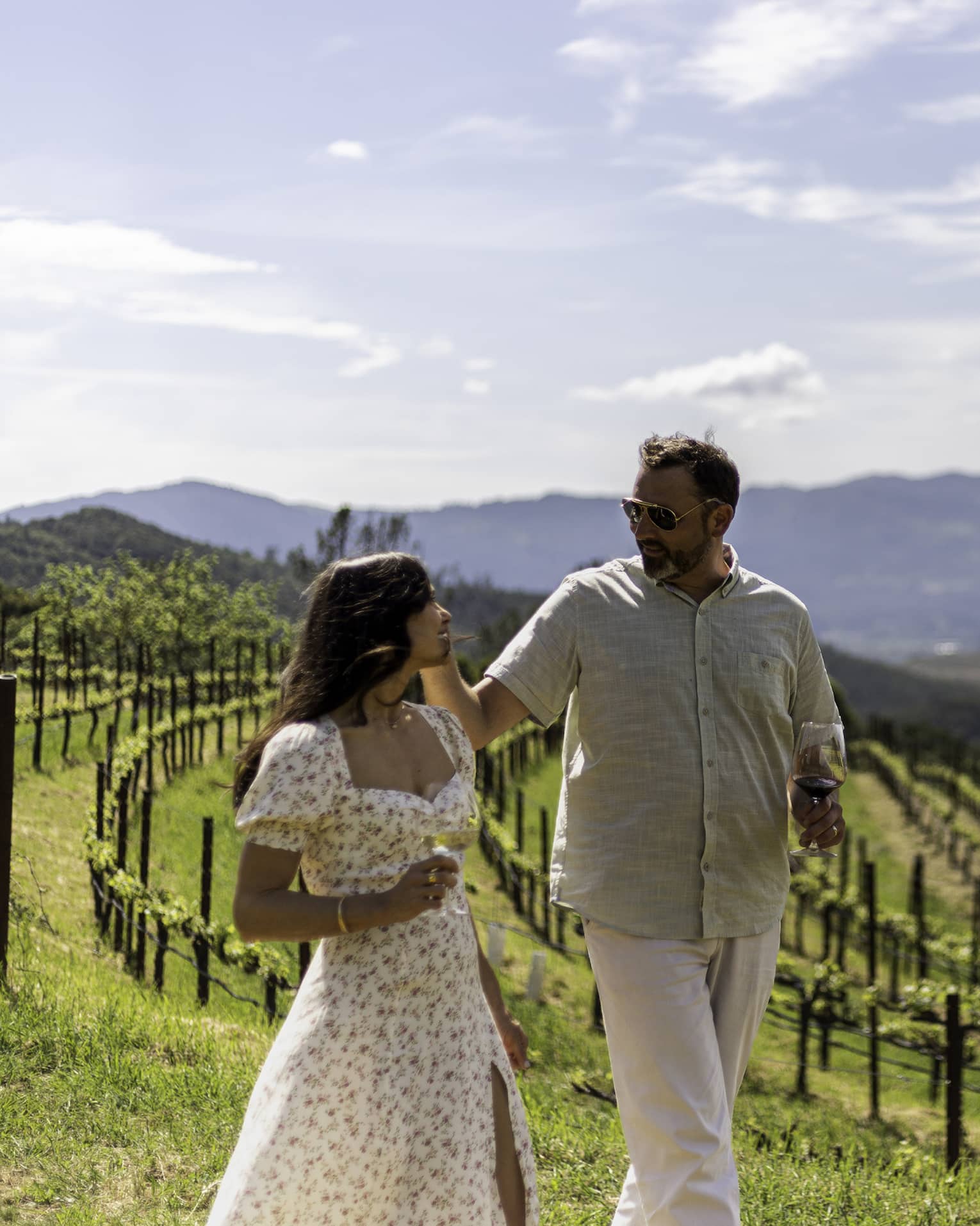 Two guests walking through a vineyard with the mountains in the background.