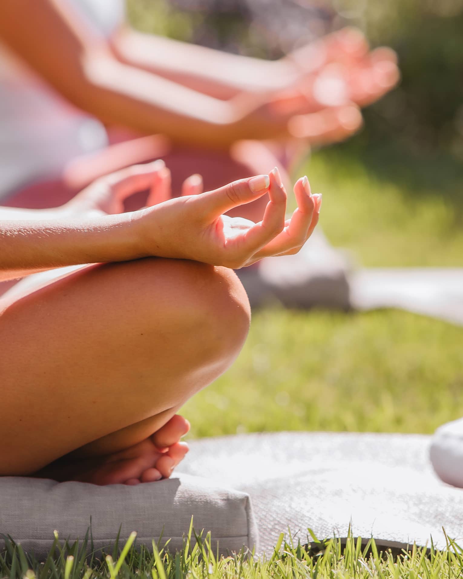 A group doing yoga outside with mats and towels.