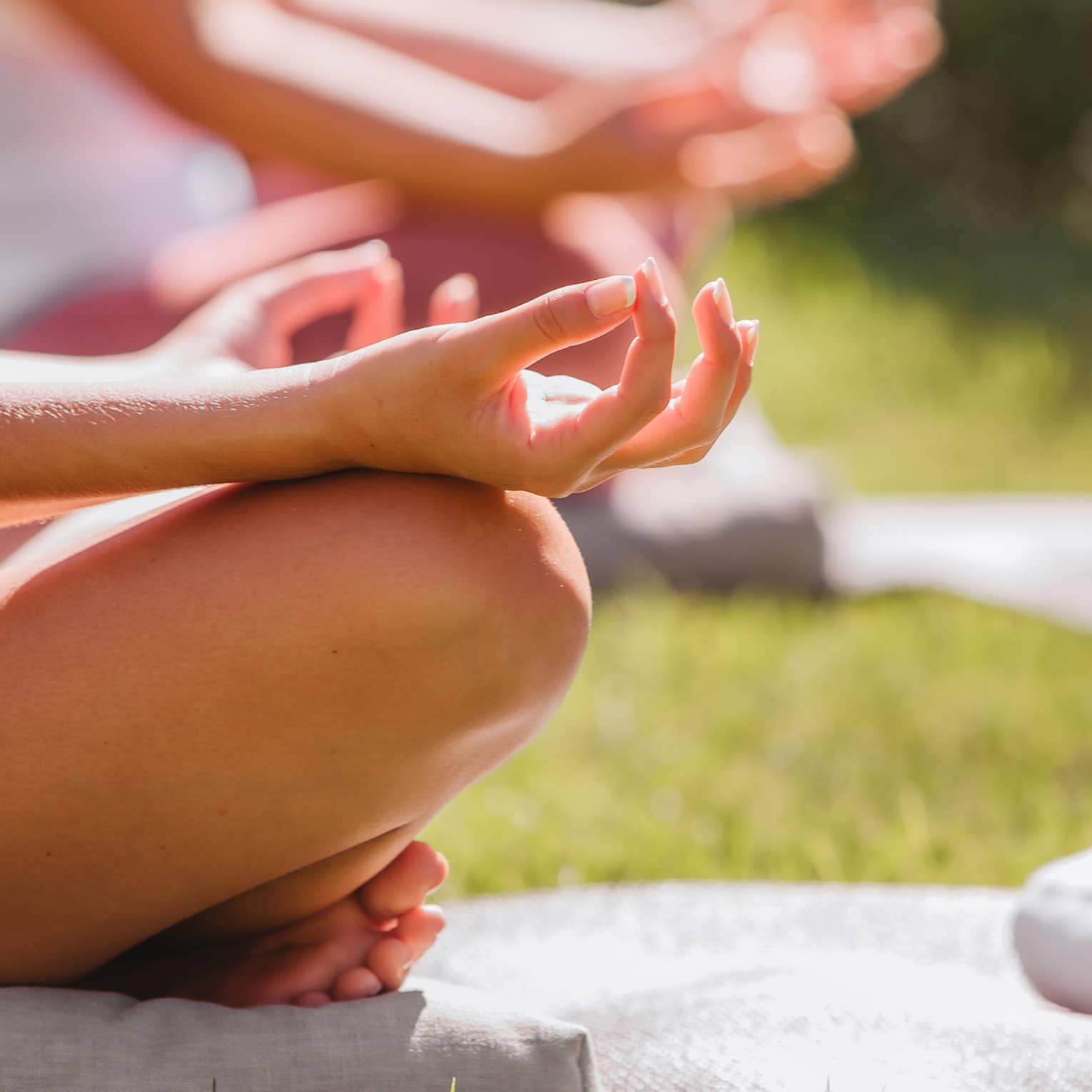 A group doing yoga outside with mats and towels.