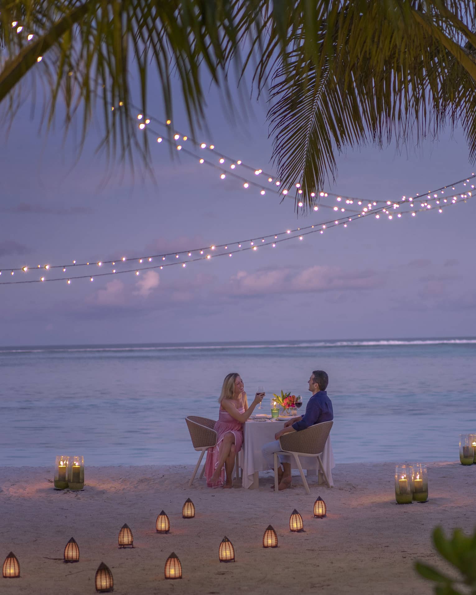 Man and woman dine at table for two alone on decorated beach