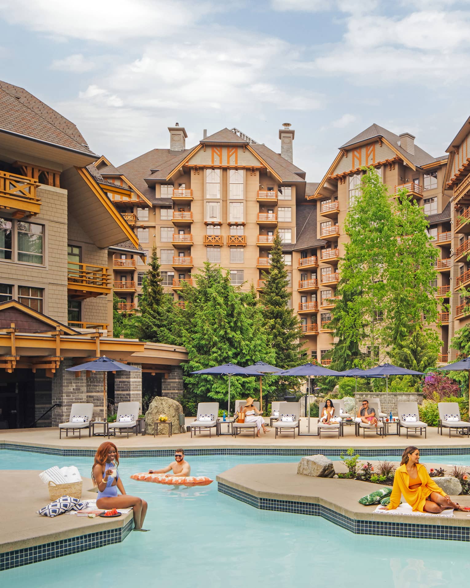 People lounging around an outdoor pool with large hotel buildings in the background.
