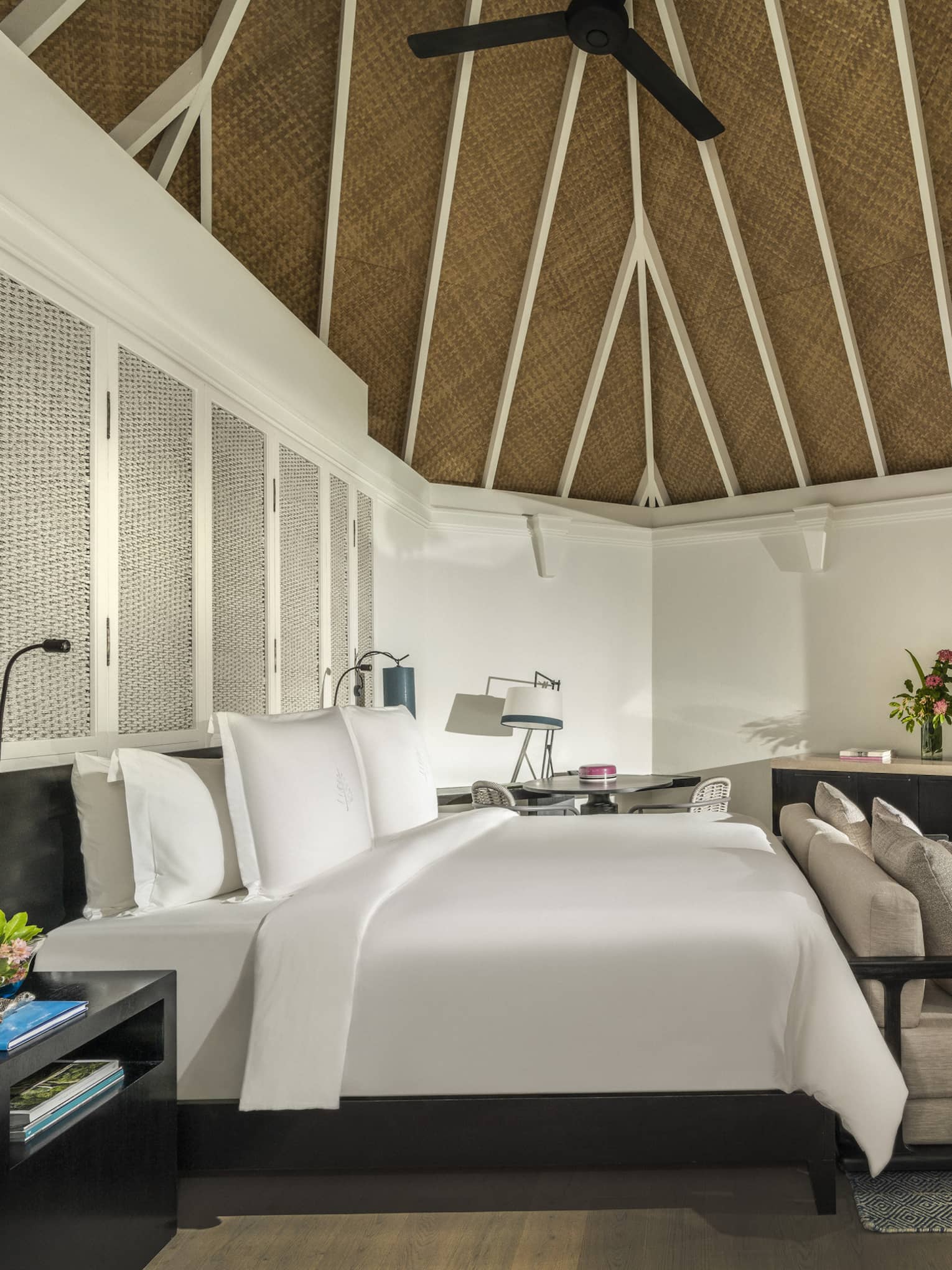 Beach pavilion bedroom with a king-size bed, vaulted thatched ceiling, cozy seating area and a flatscreen TV