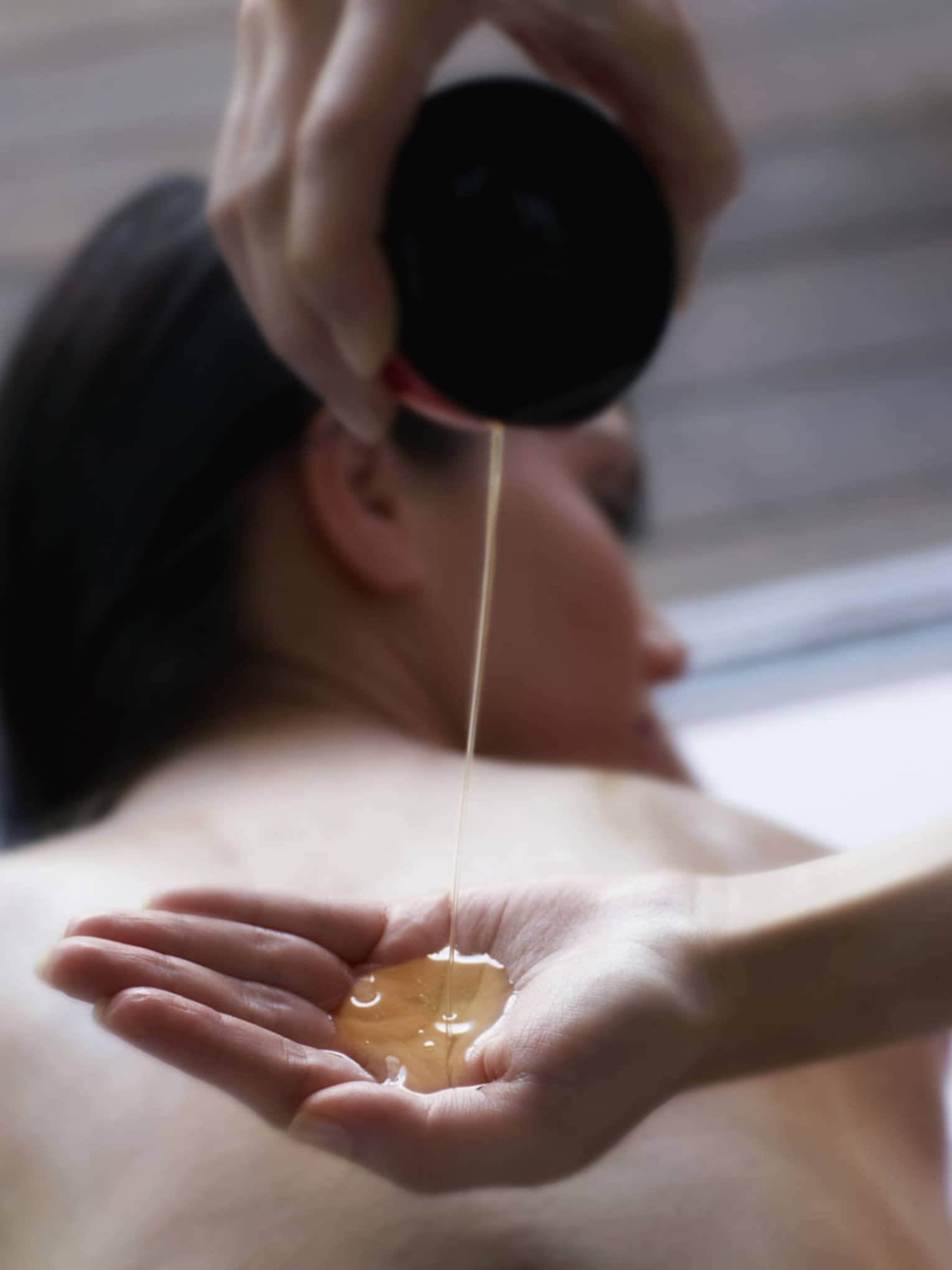 Stream of spa oil falls into open hand
