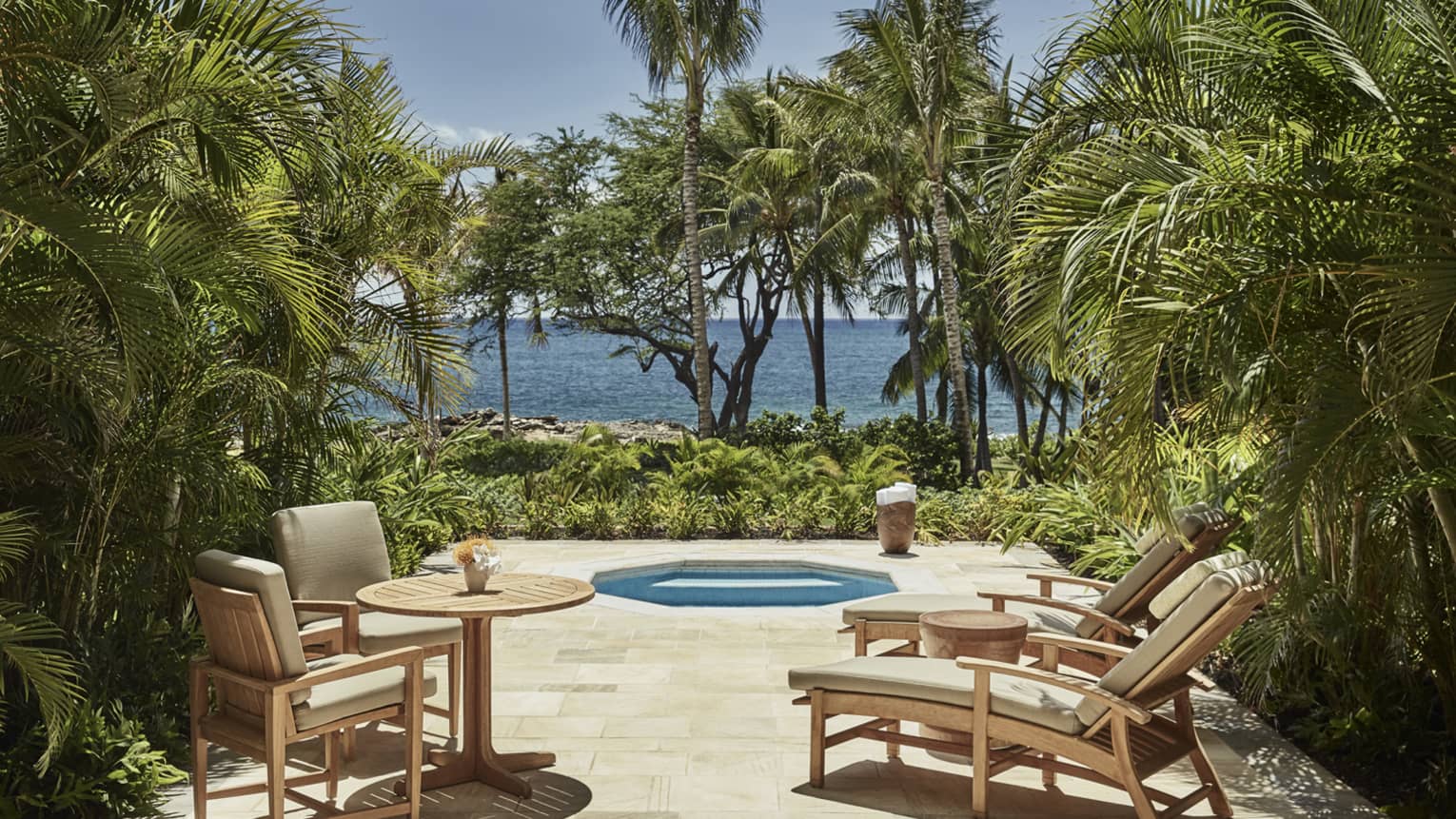 Deluxe Jacuzzi Room patio with chairs around octagon-shaped jacuzzi tub on palm-lined patio