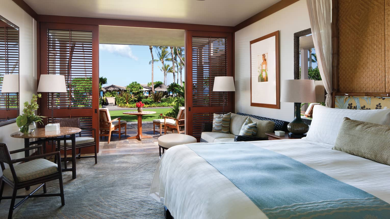 Partial Ocean-View Room bed with blue blanket, loveseat, cafe table by open wall, wood shutters