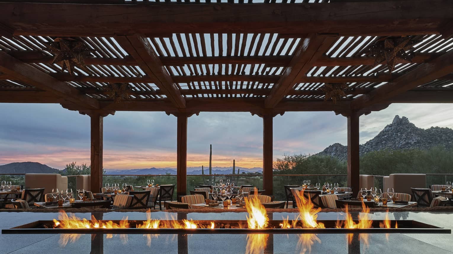 A fire warms the outdoor terrace as the sun sets of the city 