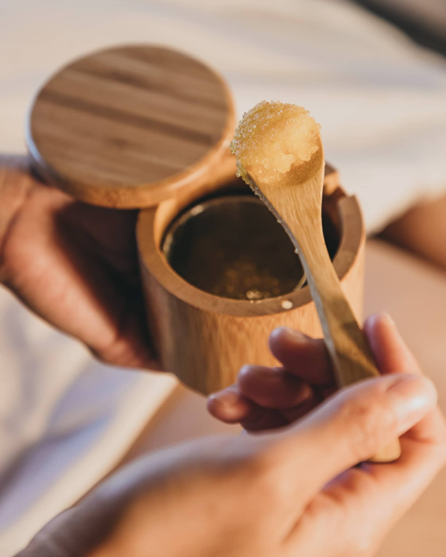 A spa staff member scoops some sugar scrub out of a bamboo container in Hawaii