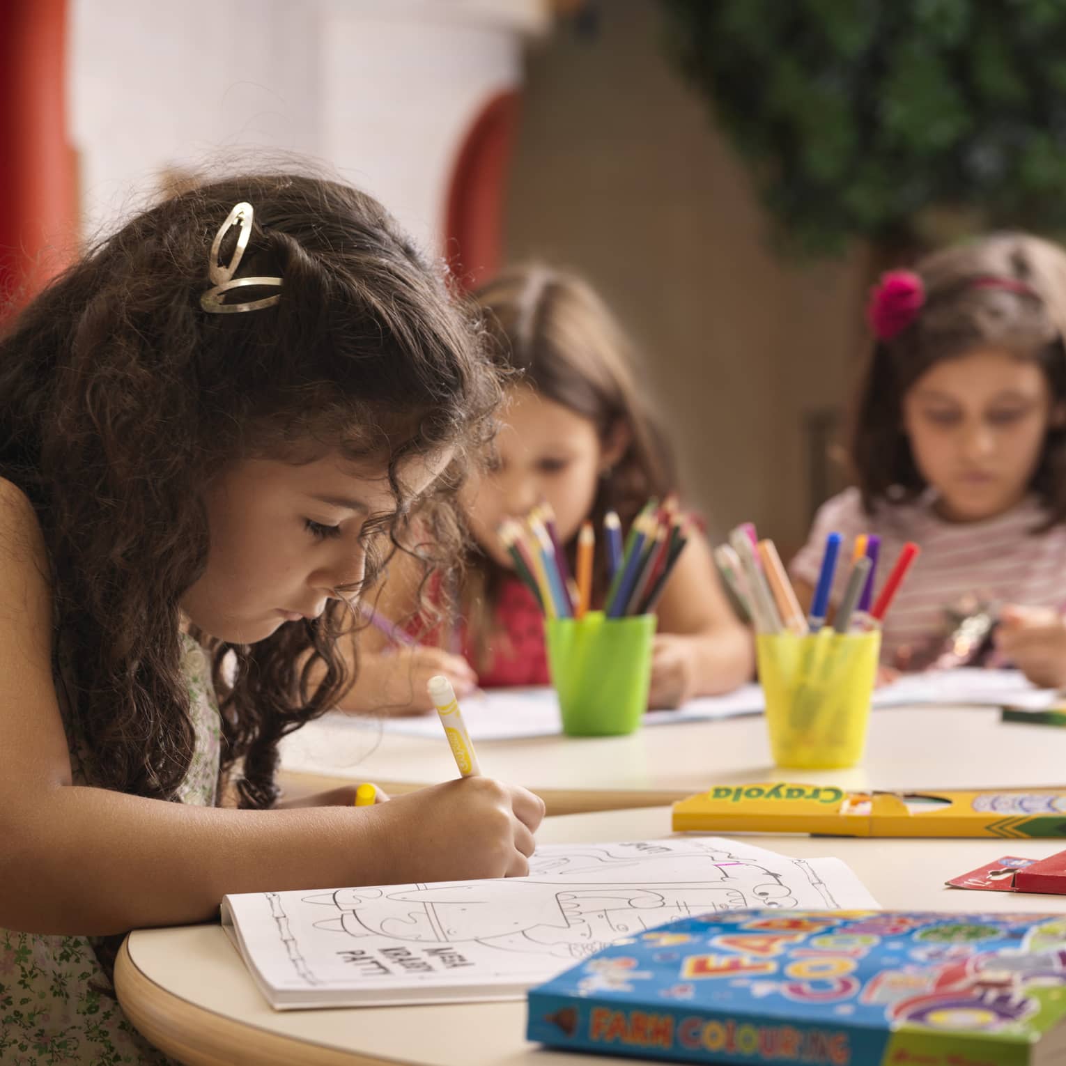 A group of young girls using markers on colouring books.