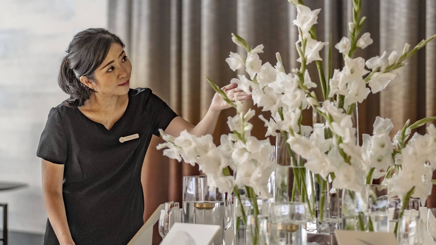 Florist tends to a large white tabletop floral arrangement in the ballroom