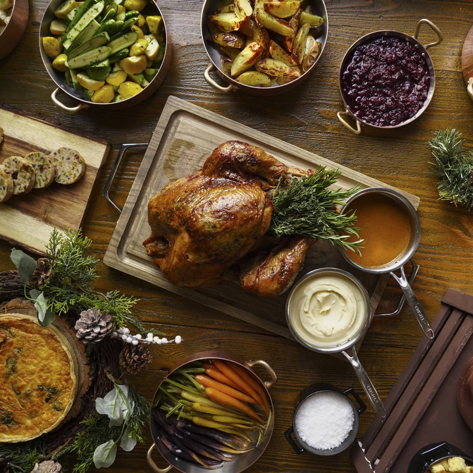 A full festive feast with a Turkey in the centre, and several copper pots of stewed vegetables surrounding
