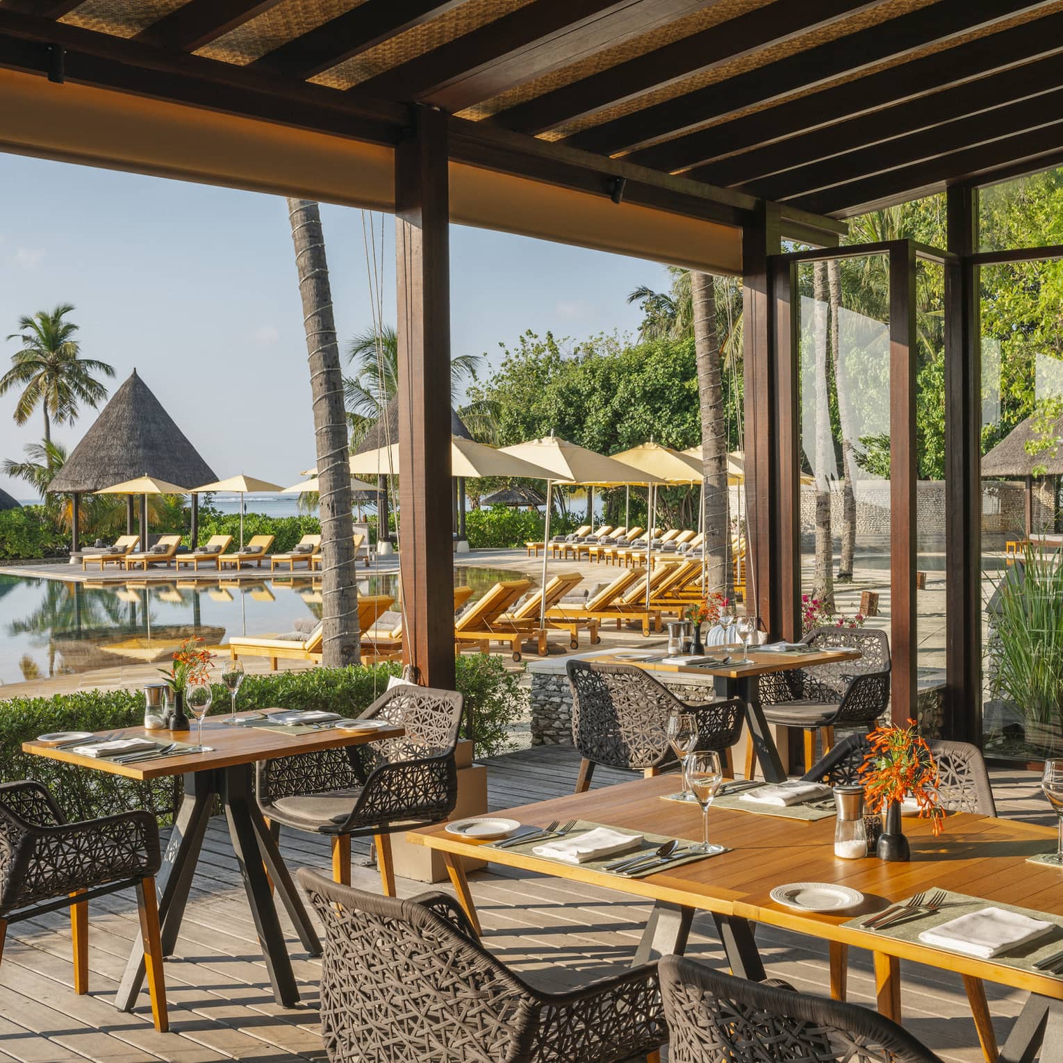 Open-air restaurant Caf� Huraa with rattan chairs and blonde wood tables, overlooking the pool
