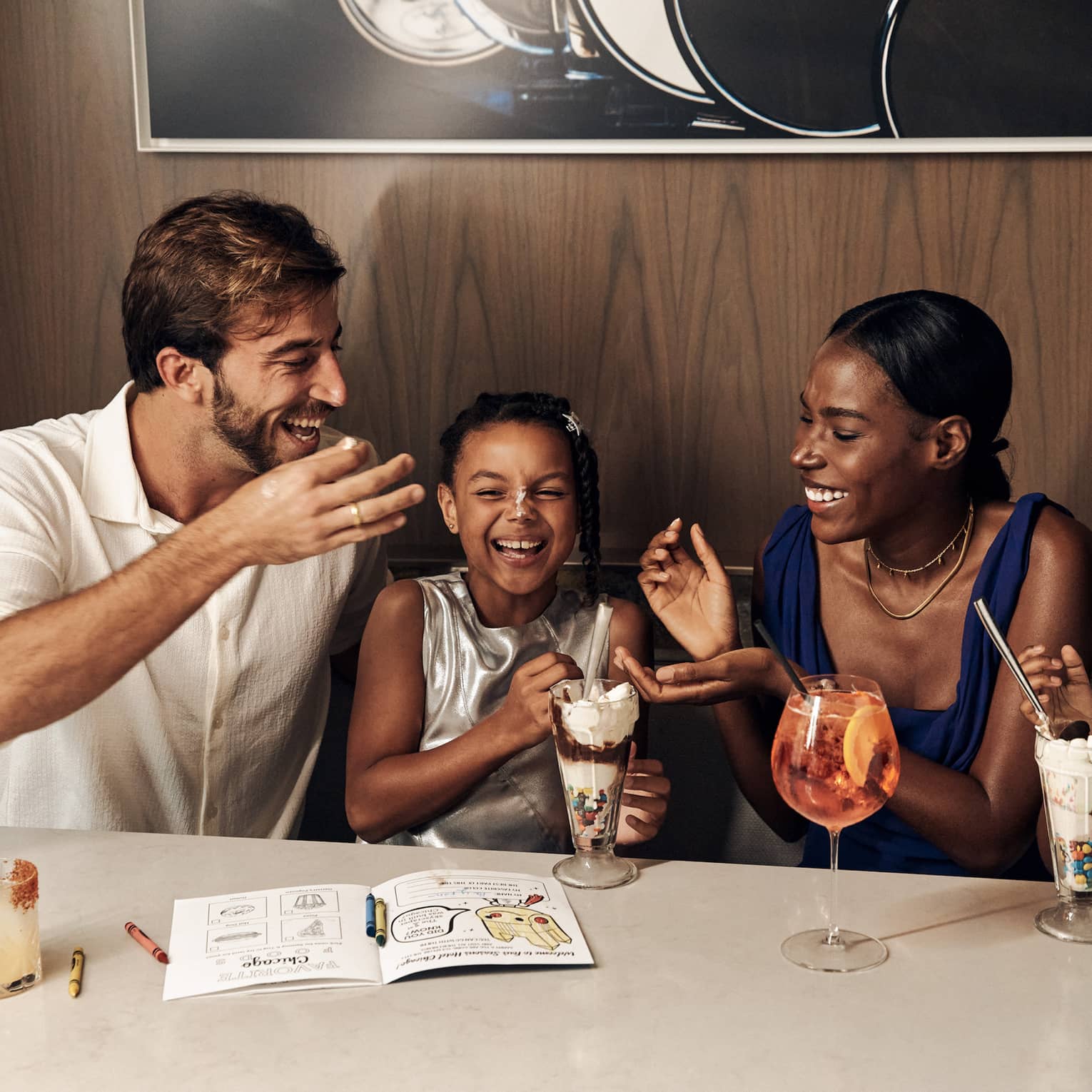Family sitting at the table laughing and eating ice cream sundaes.