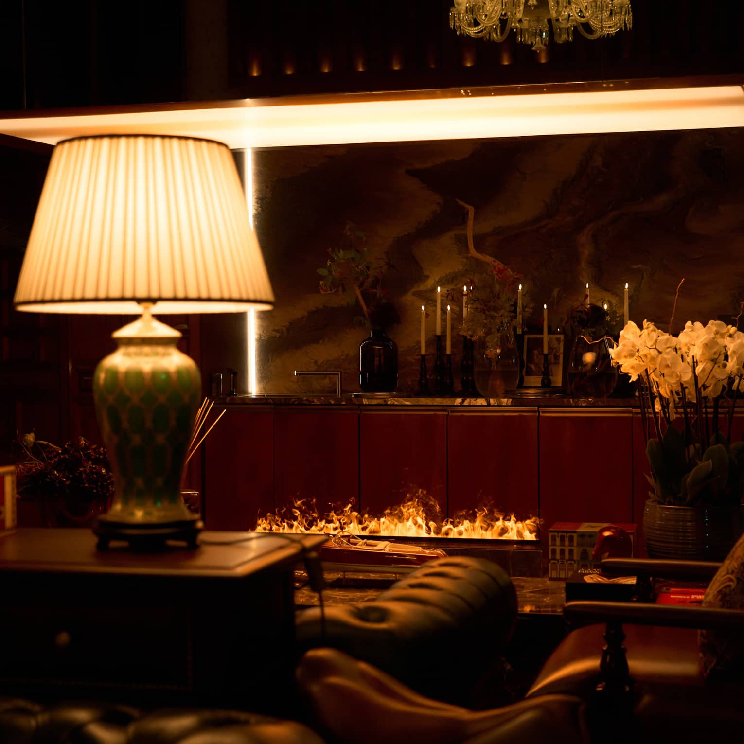 Restaurant lounge area with large lamp, arm chairs and an open-flame fireplace