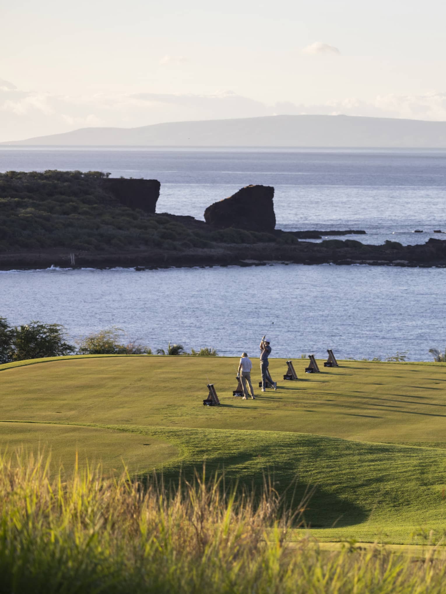 Golfers practicing on ocean-side golf course in Lanai, Hawaii