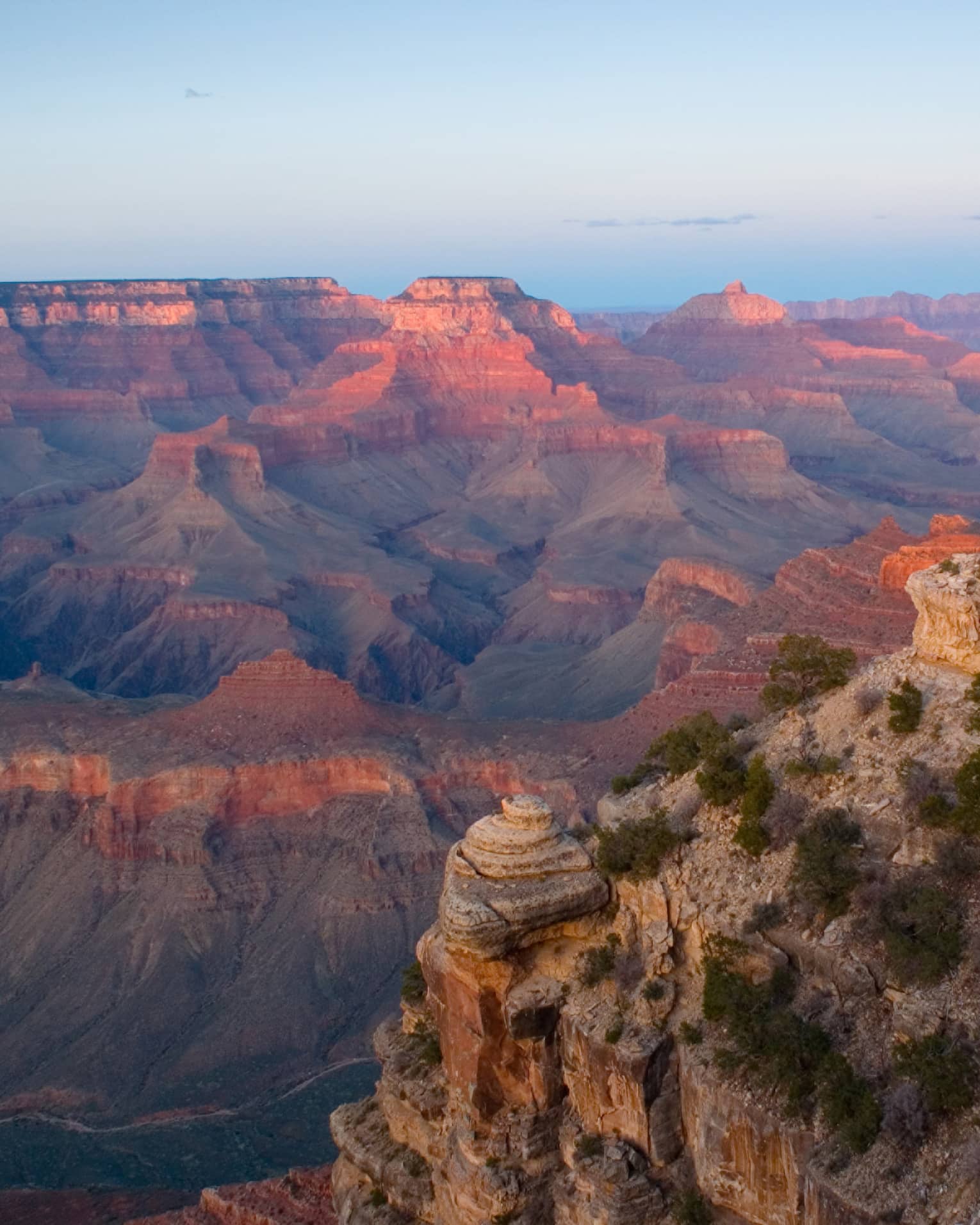 Sweeping view of Grand Canyon cliffs, canyon ridges, pink light from sunset
