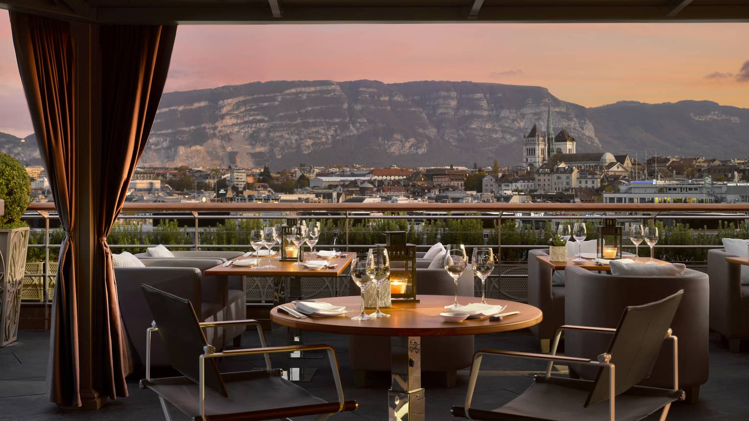 Close-up of patio dining table with wine glasses, sunset view of mountains