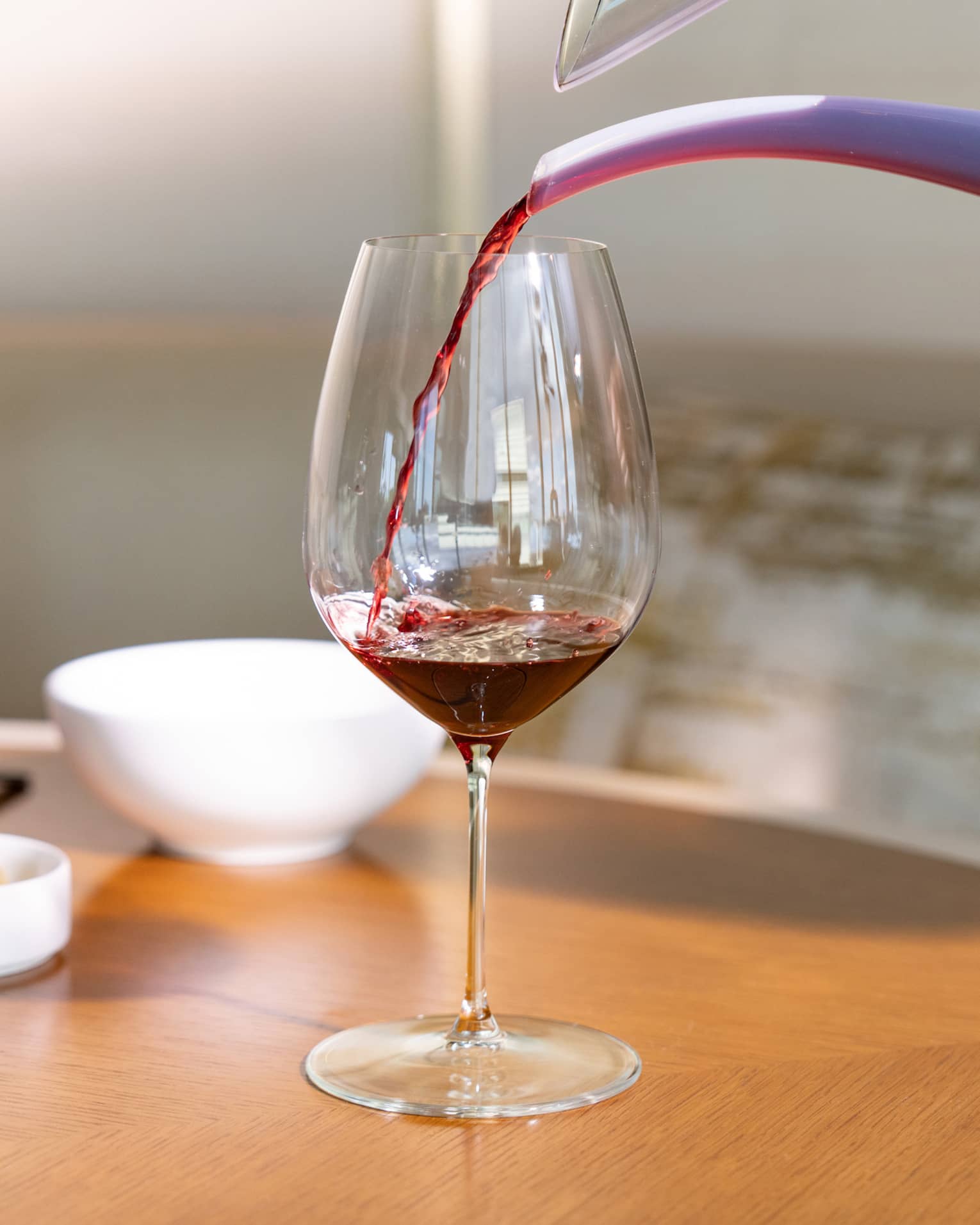 Red wine is poured into a glass from a decanter