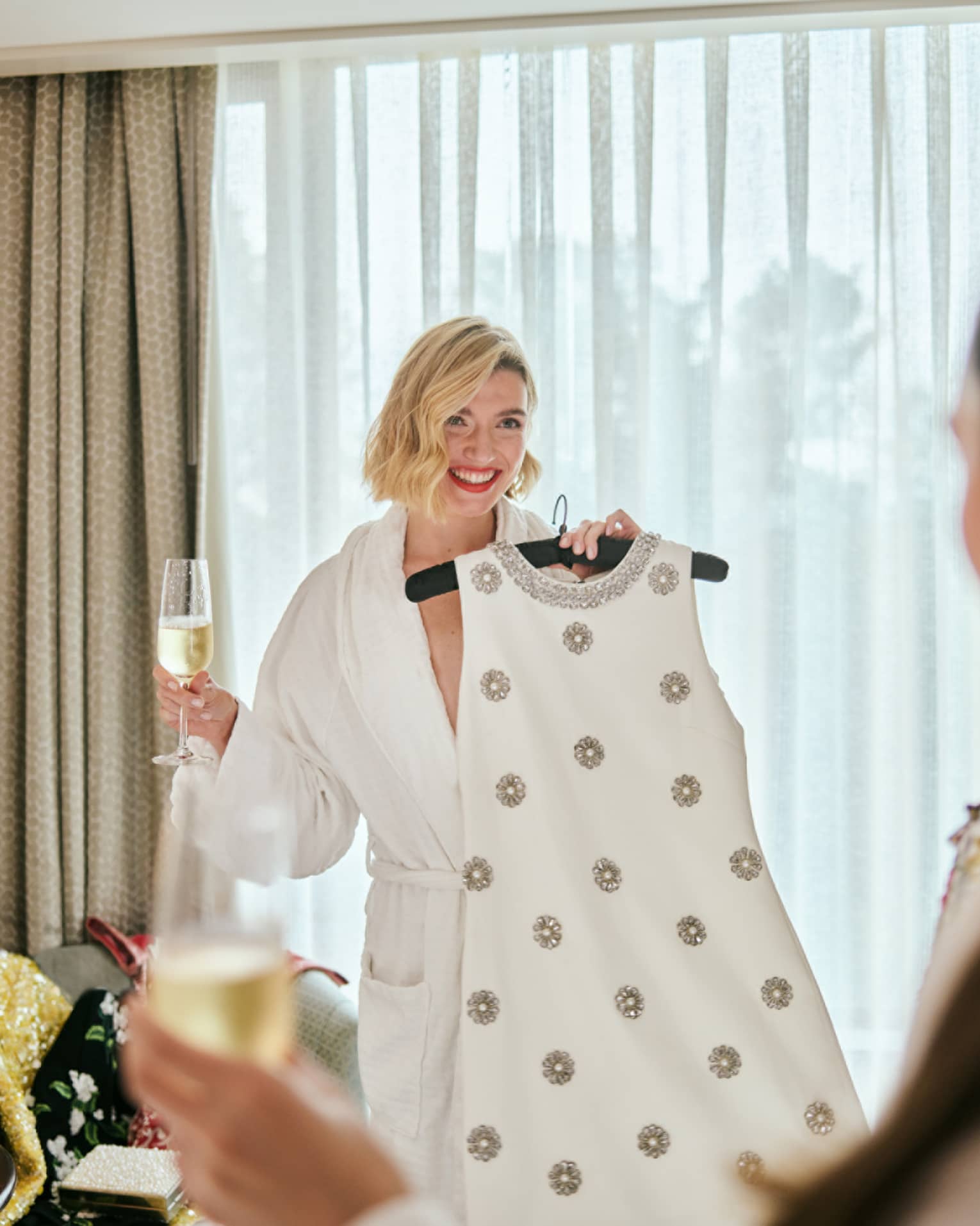 A person wearing a robe and holding a dress on a hanger