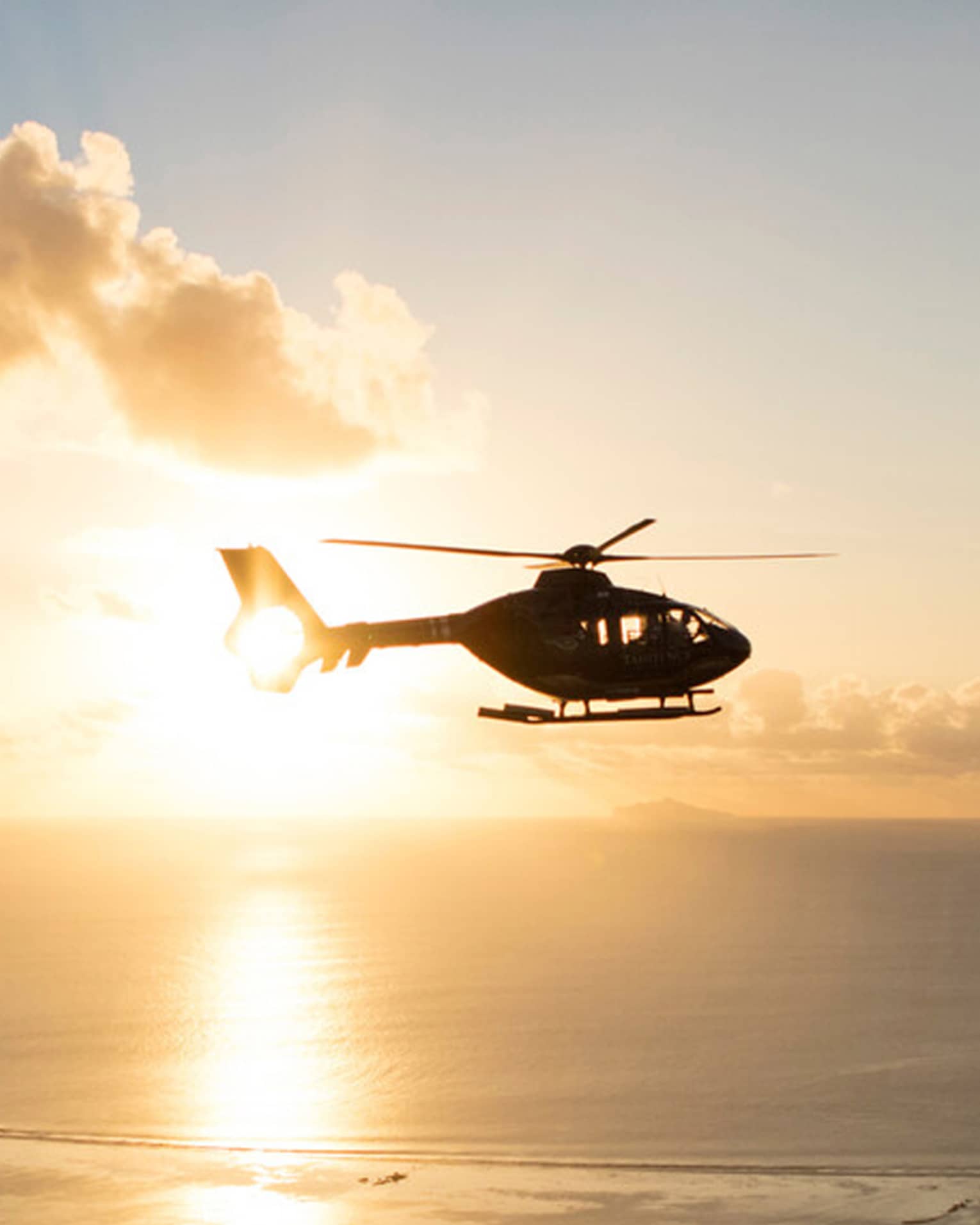 Helicopter over the sea at sunset