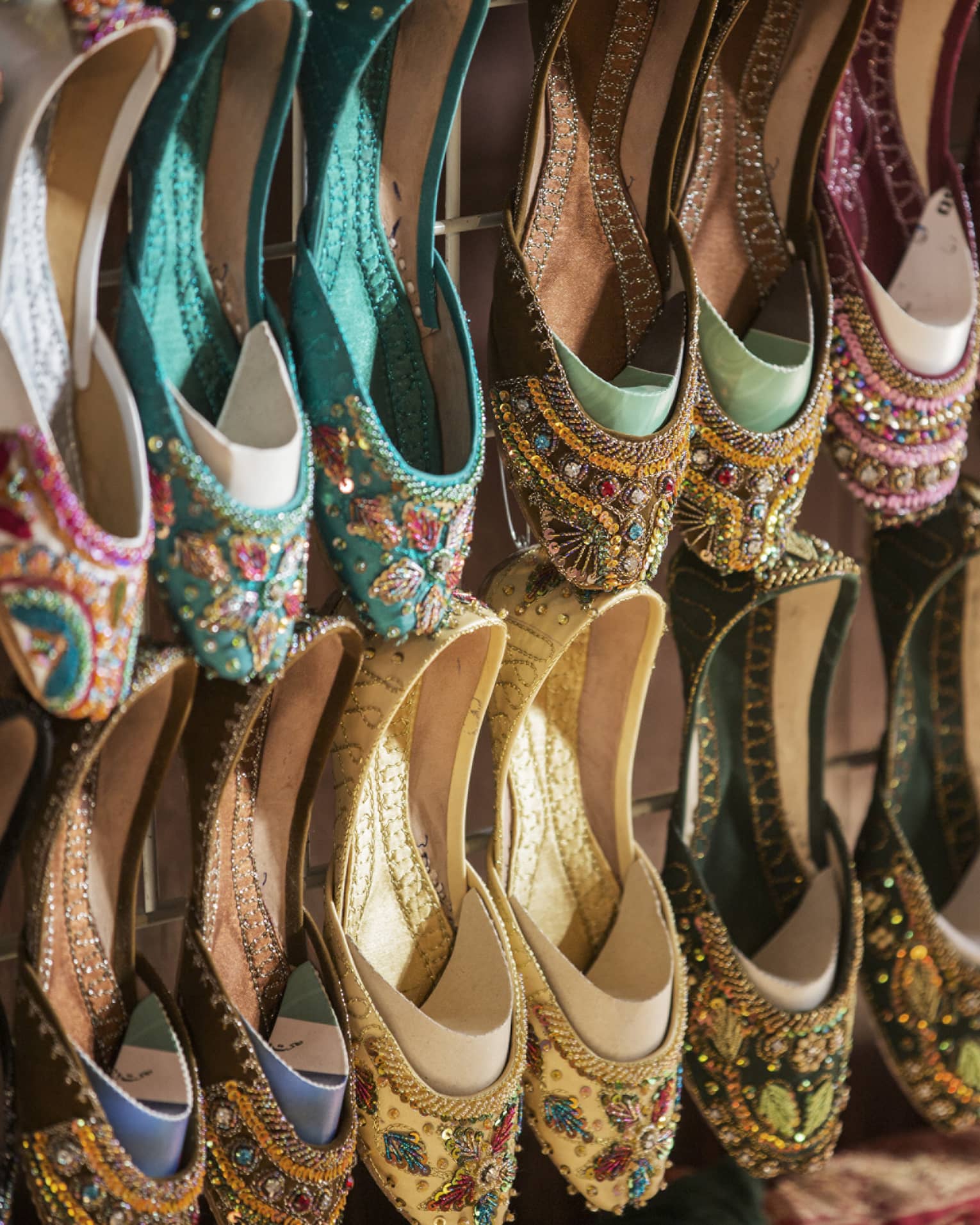Rows of colourful shoes with beadwork and embroidery hang from market wall
