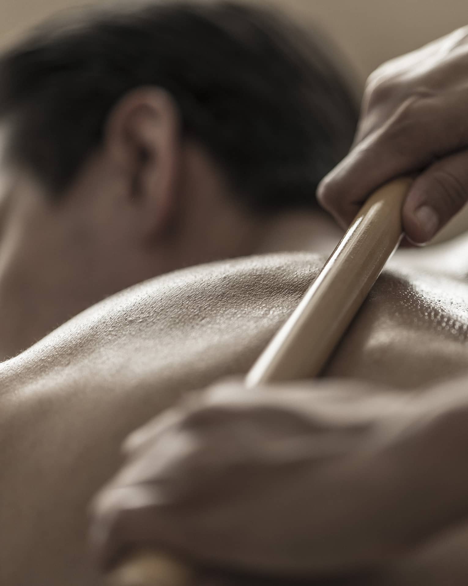A spa attendant uses a tool to massage a guest's back