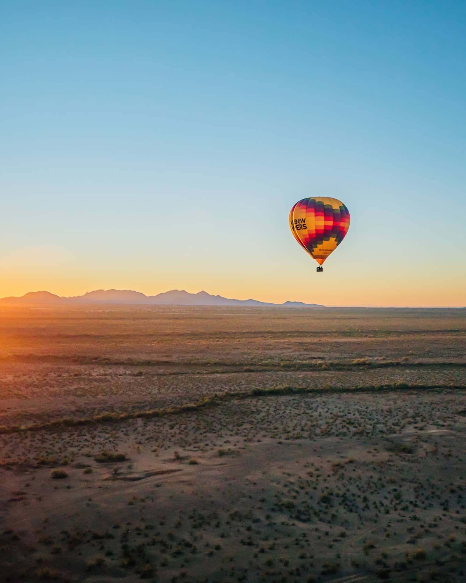 Two hot air balloons floating over a large desert.